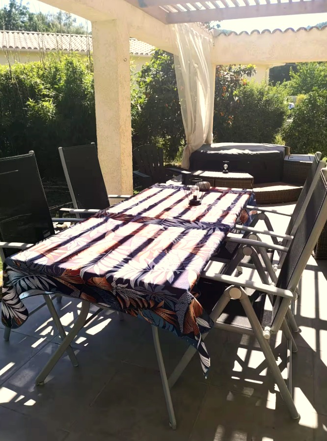 Terrasse extérieure sous pergola, table dressée et jacuzzi