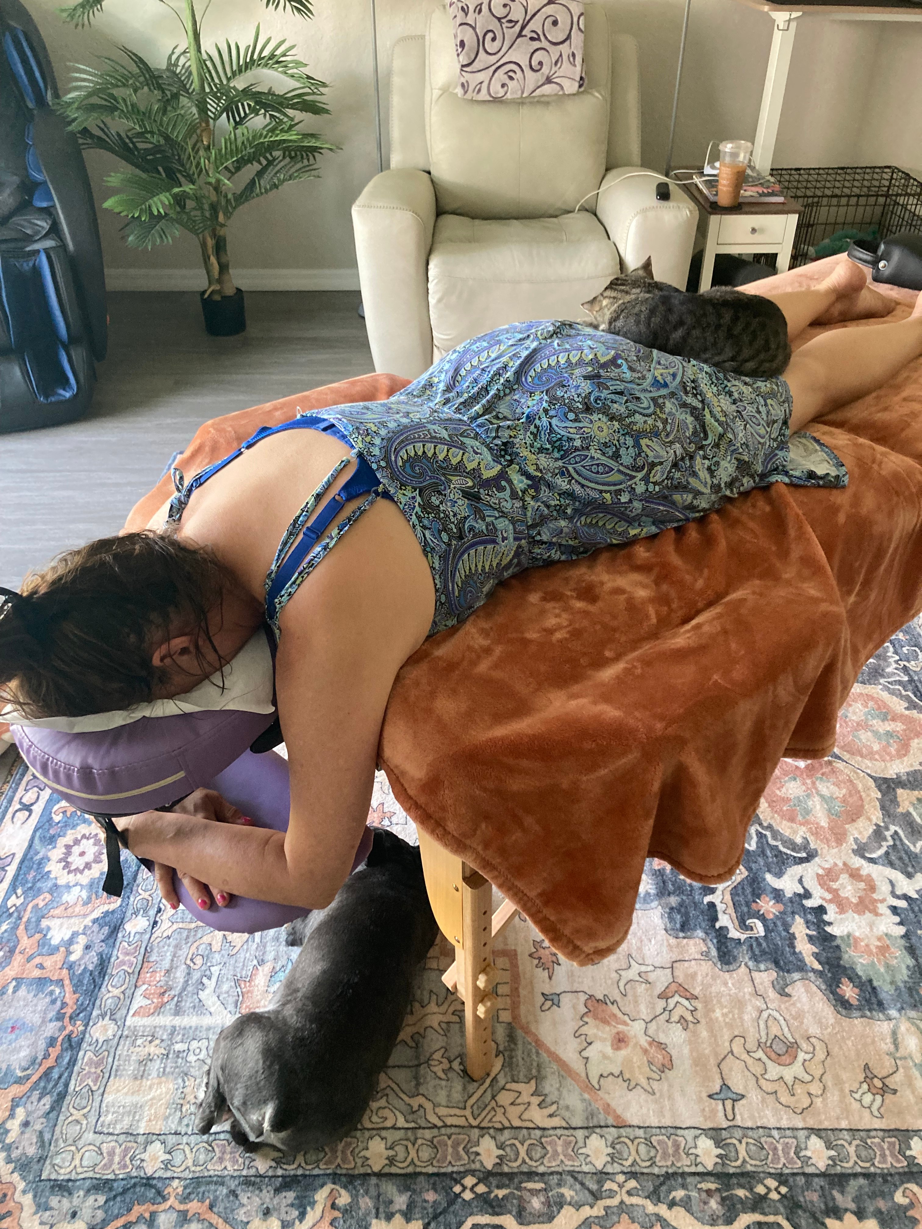 Client enjoying a Spinal Flow session at home with cozy blankets and cats nearby