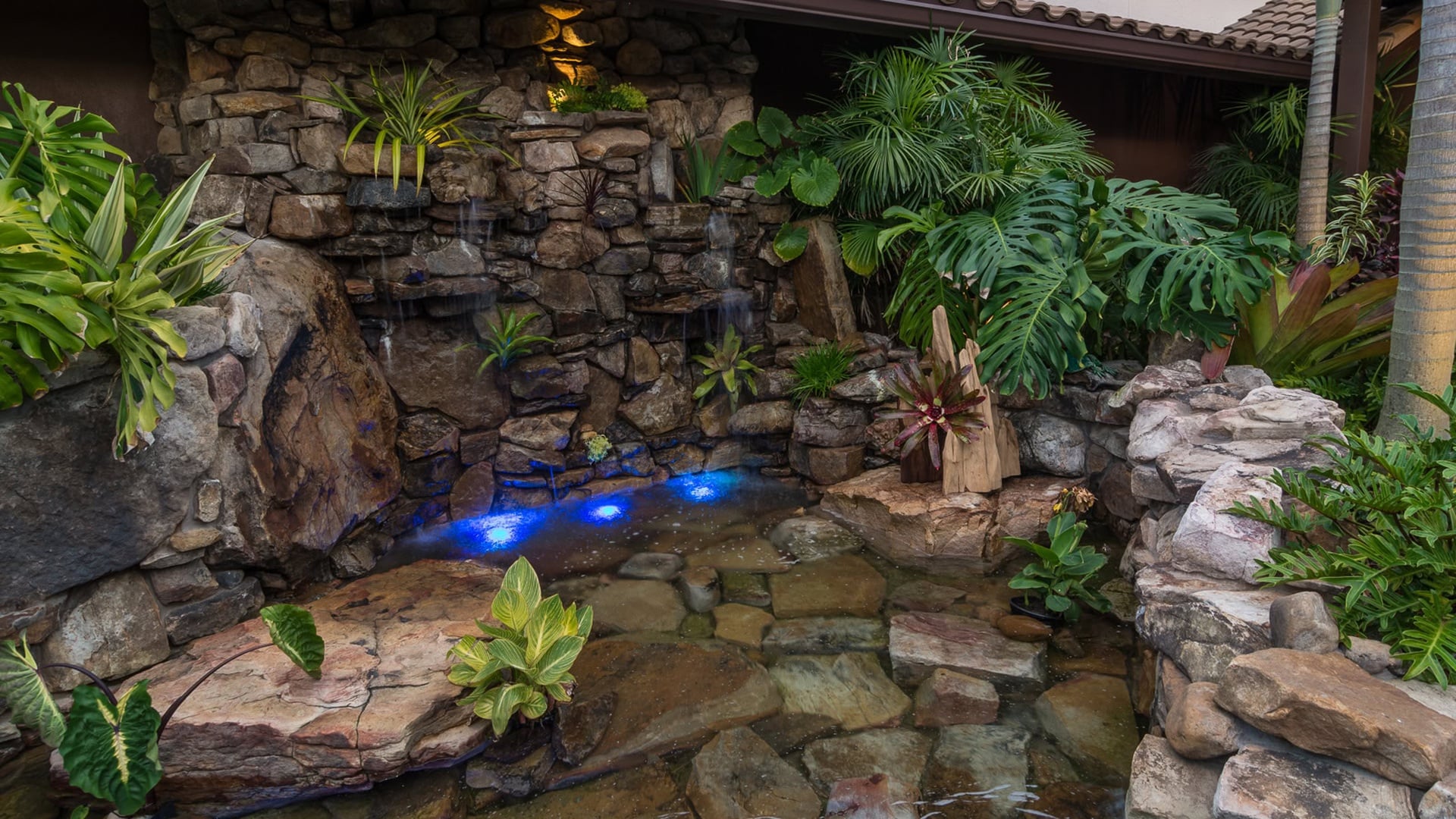 Pool with natural rock waterfall and tropical plants