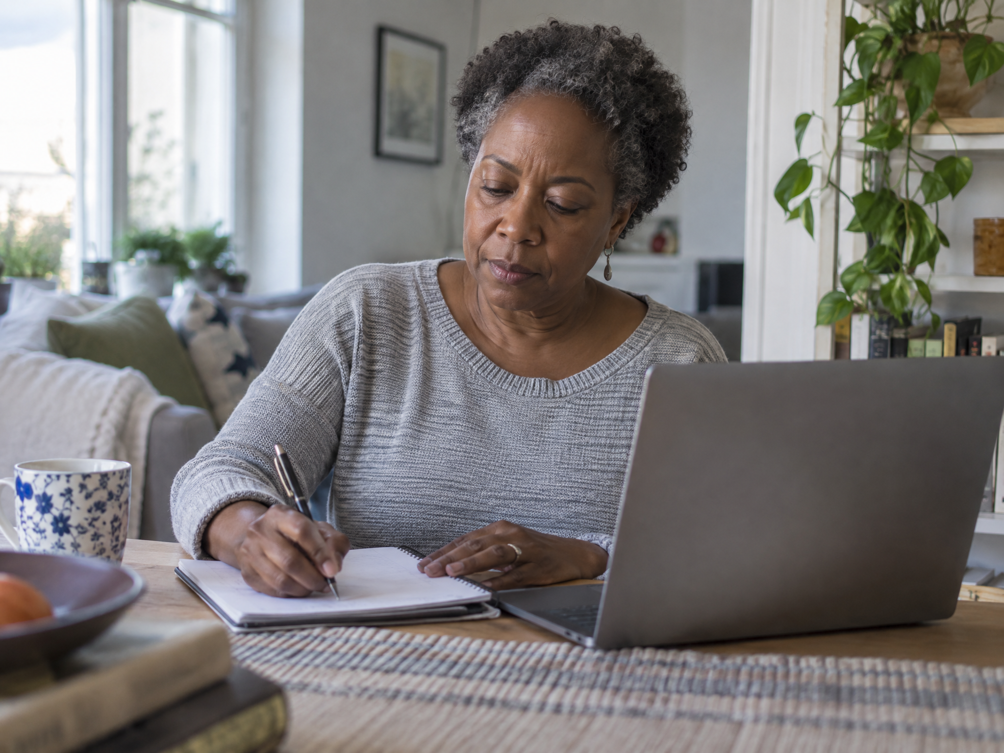 Veteran writing down her ratings in a notebook beside her laptop at home