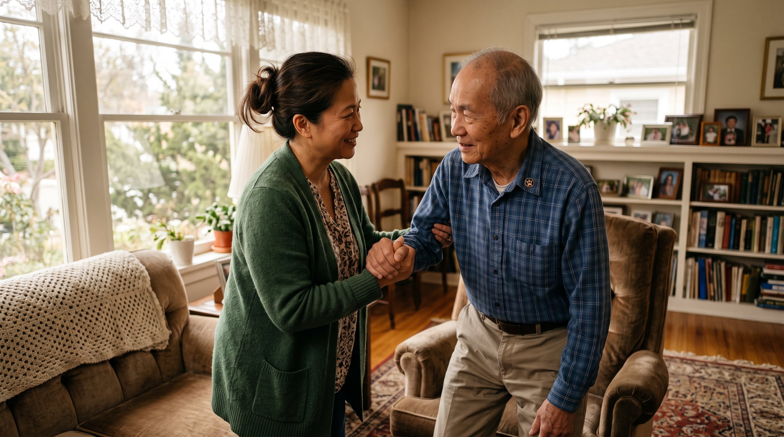 A middle-aged Asian American daughter lovingly steadying her elderly Asian American veteran father at home