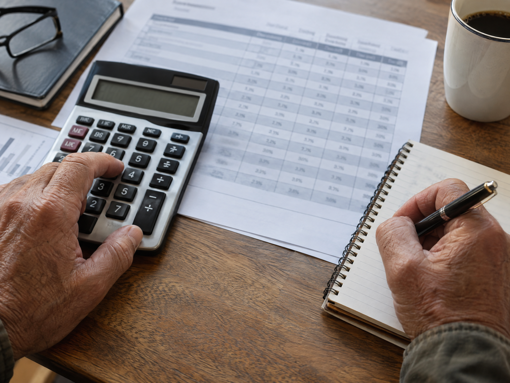 Hands working rating math on a calculator beside a printed percentage table