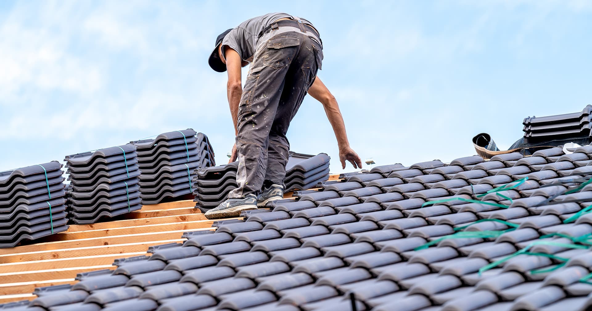 Roofer laying new tiles on a fresh roof
