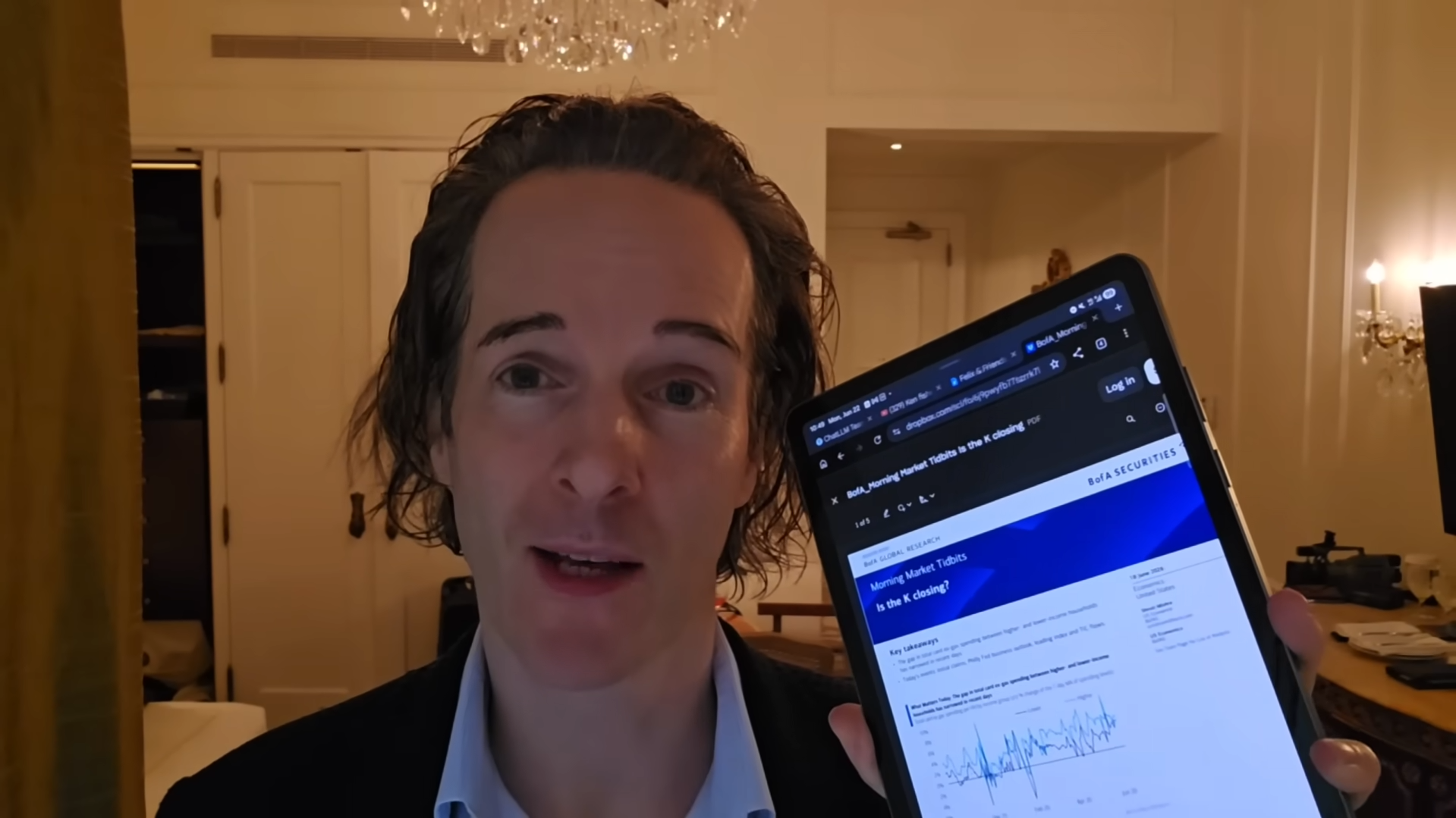 Felix Nikolas Prehn holding up a tablet displaying a market chart, with a warmly lit room behind him