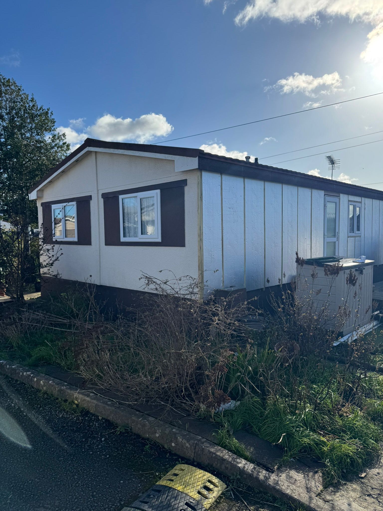 Older park home with deteriorated cream and brown exterior needing full refurbishment