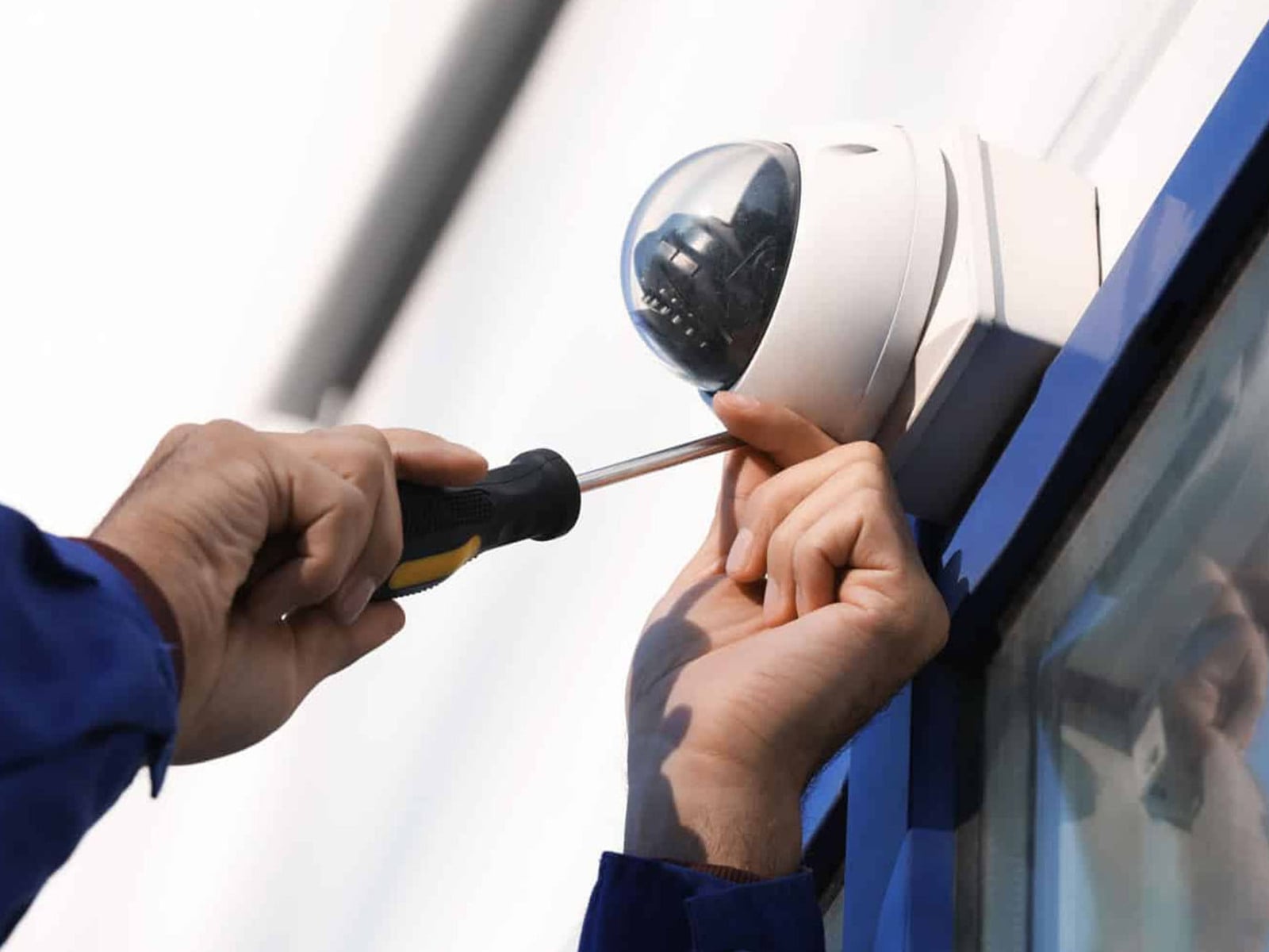 STG technician professionally installing commercial security camera on building exterior