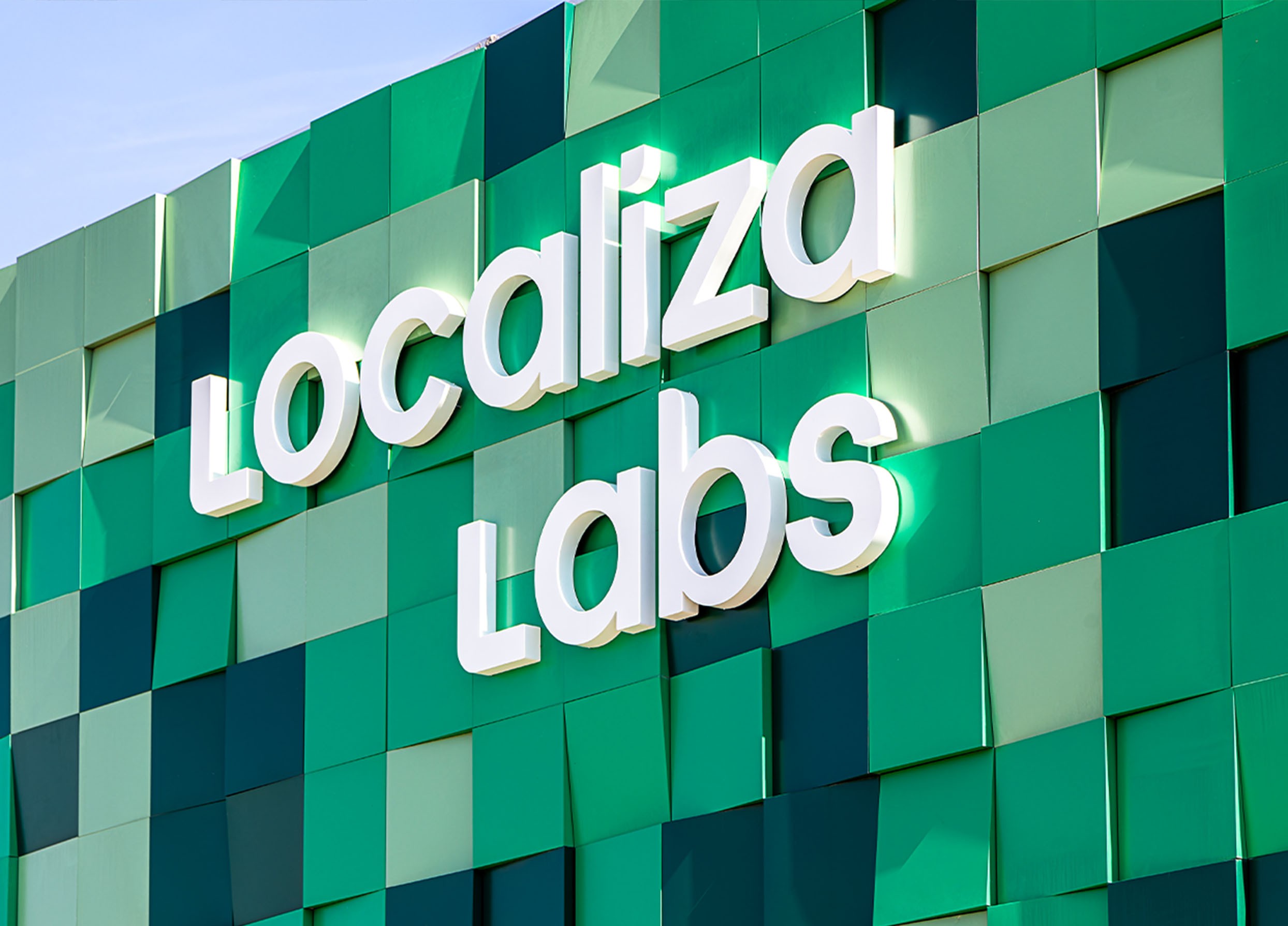 Fachada com o letreiro “Localiza Labs” sobre revestimento em painéis verdes