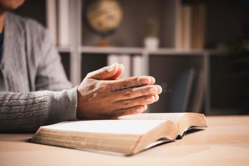 Hands in prayer over an open Bible with warm lighting at Turning Point Church