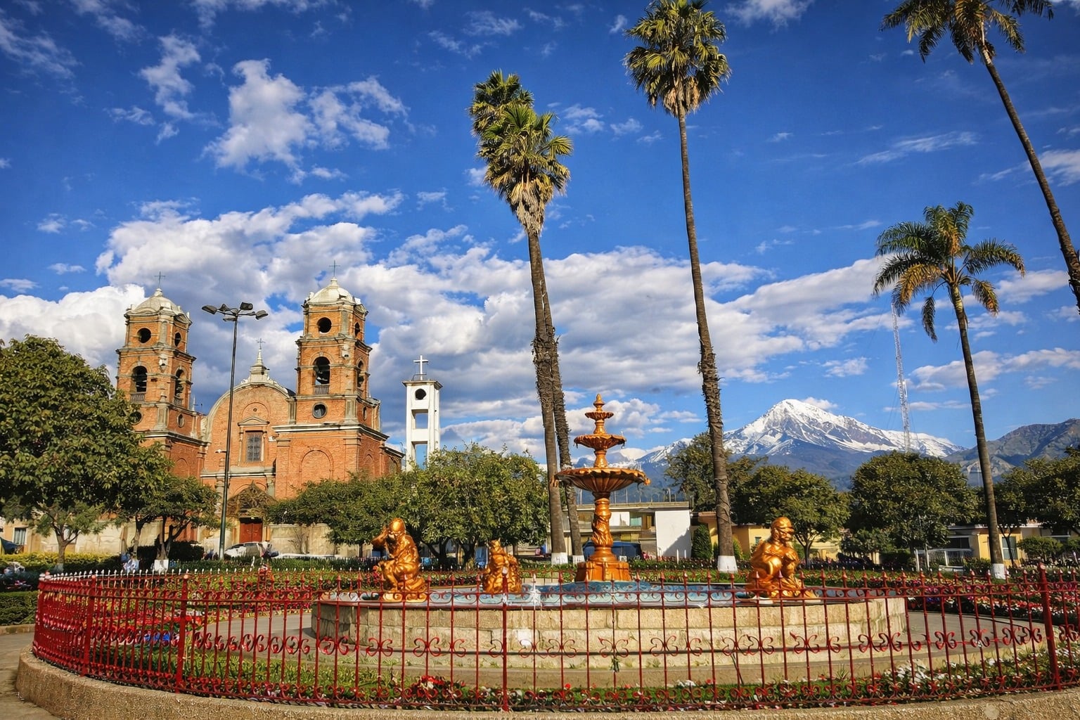 Plaza de Armas de Carhuaz con iglesia, pileta dorada, palmeras y el Huascarán nevado de fondo
