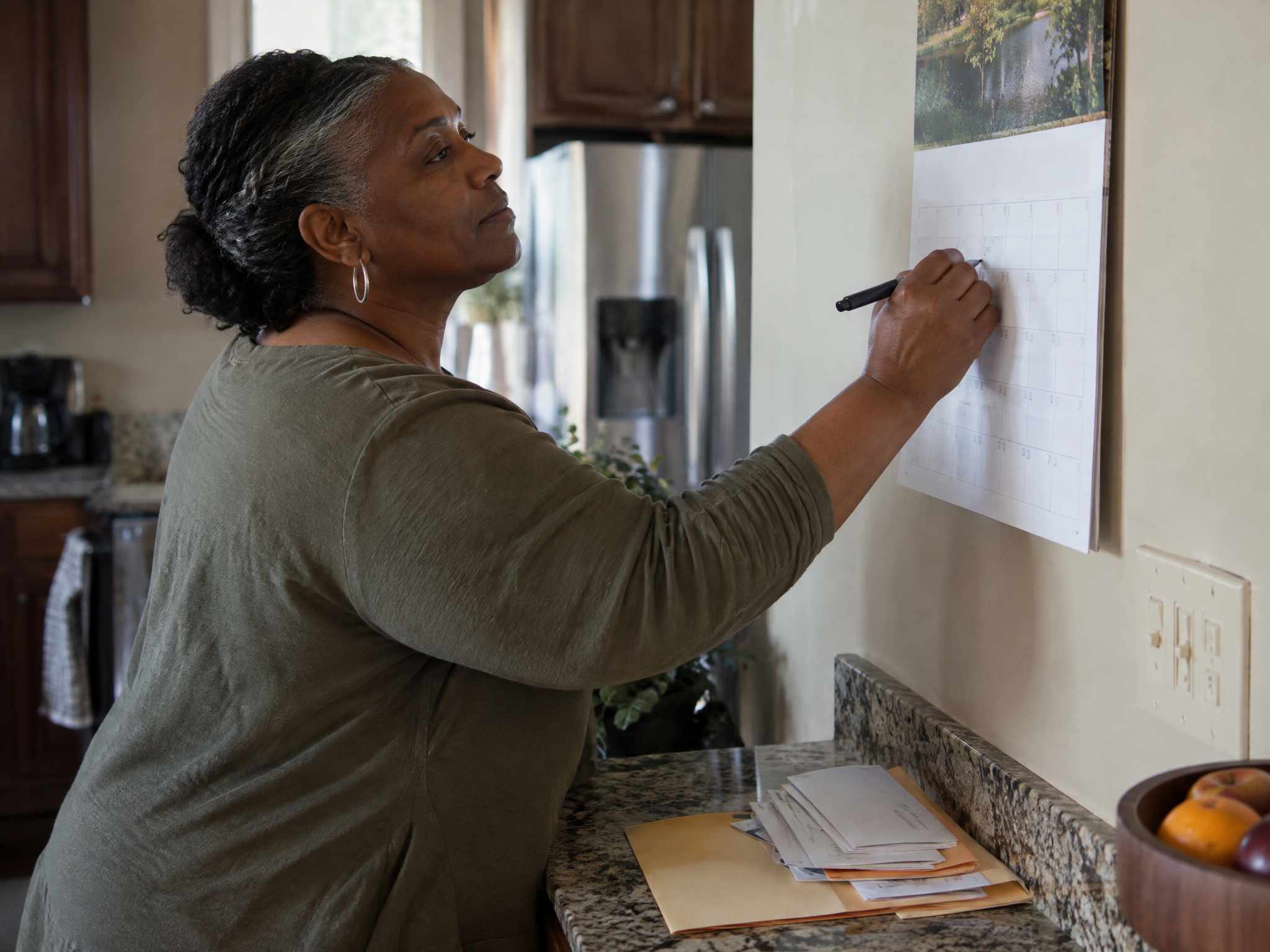 Veteran marking key dates on a kitchen wall calendar