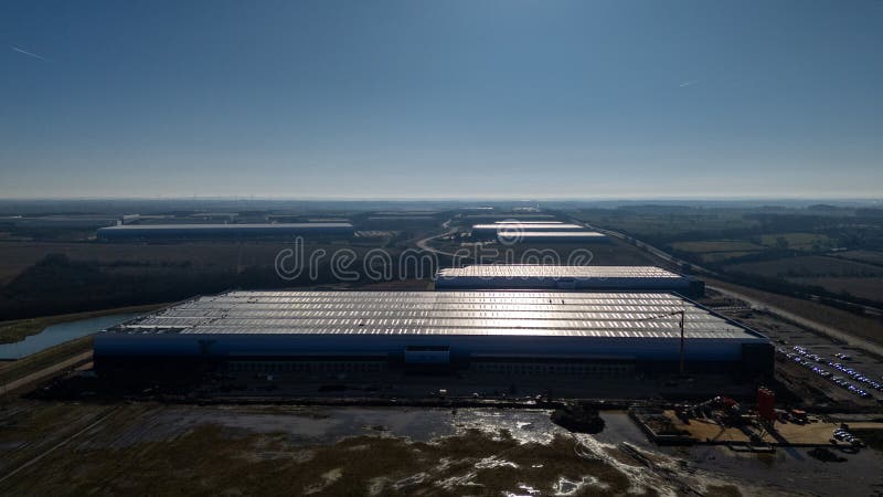 Aerial view of a large industrial warehouse with trucks at loading bays
