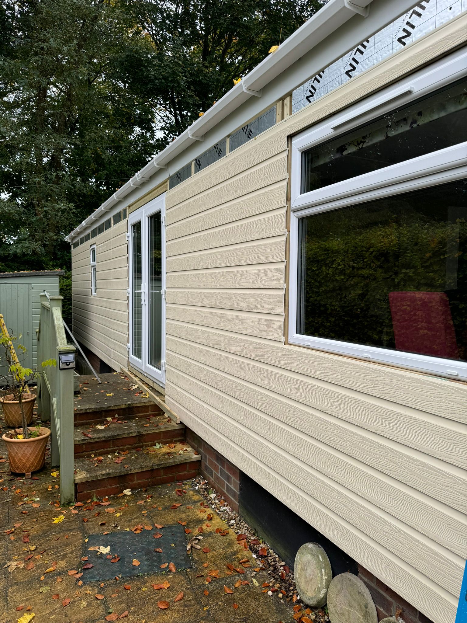 Full length view of completed park home re-cladding with new cream boards, door and windows