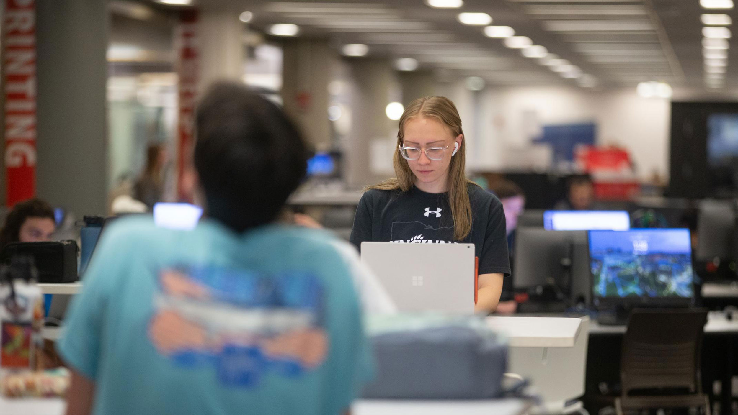 Students and researchers working with digital tools in a modern university library