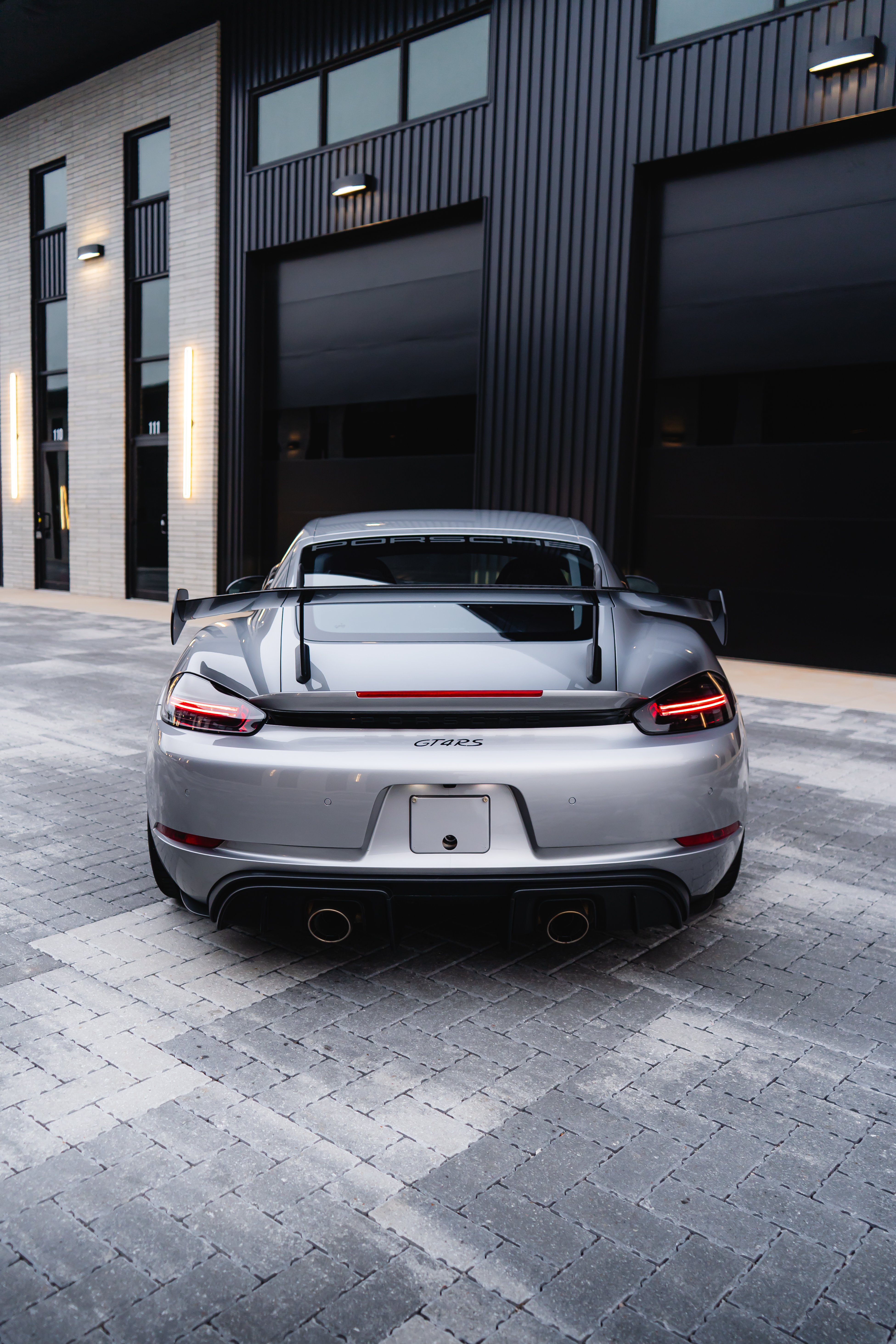 2023 Porsche 718 Cayman GT4 RS side profile in GT-Silver Metallic with carbon wing and satin black wheels