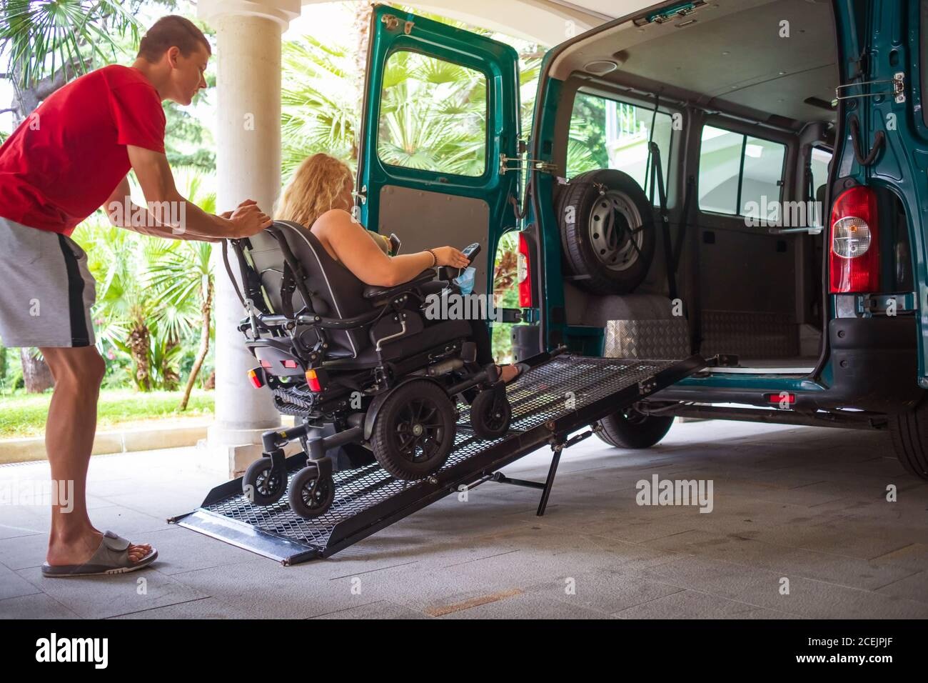 Driver assisting wheelchair user into accessible vehicle