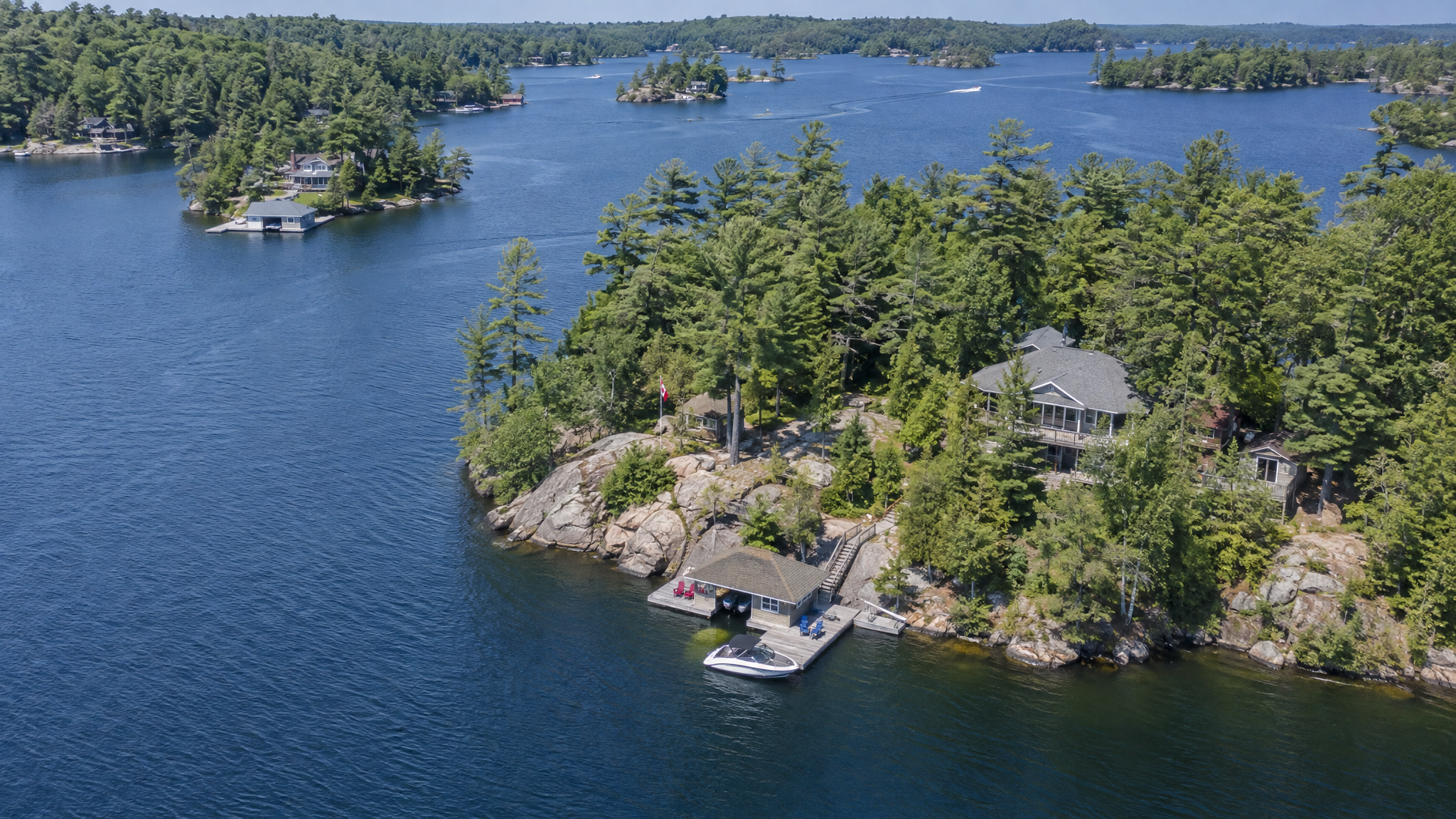 Aerial view of Muskoka lake showing cottages, docks and forested shoreline