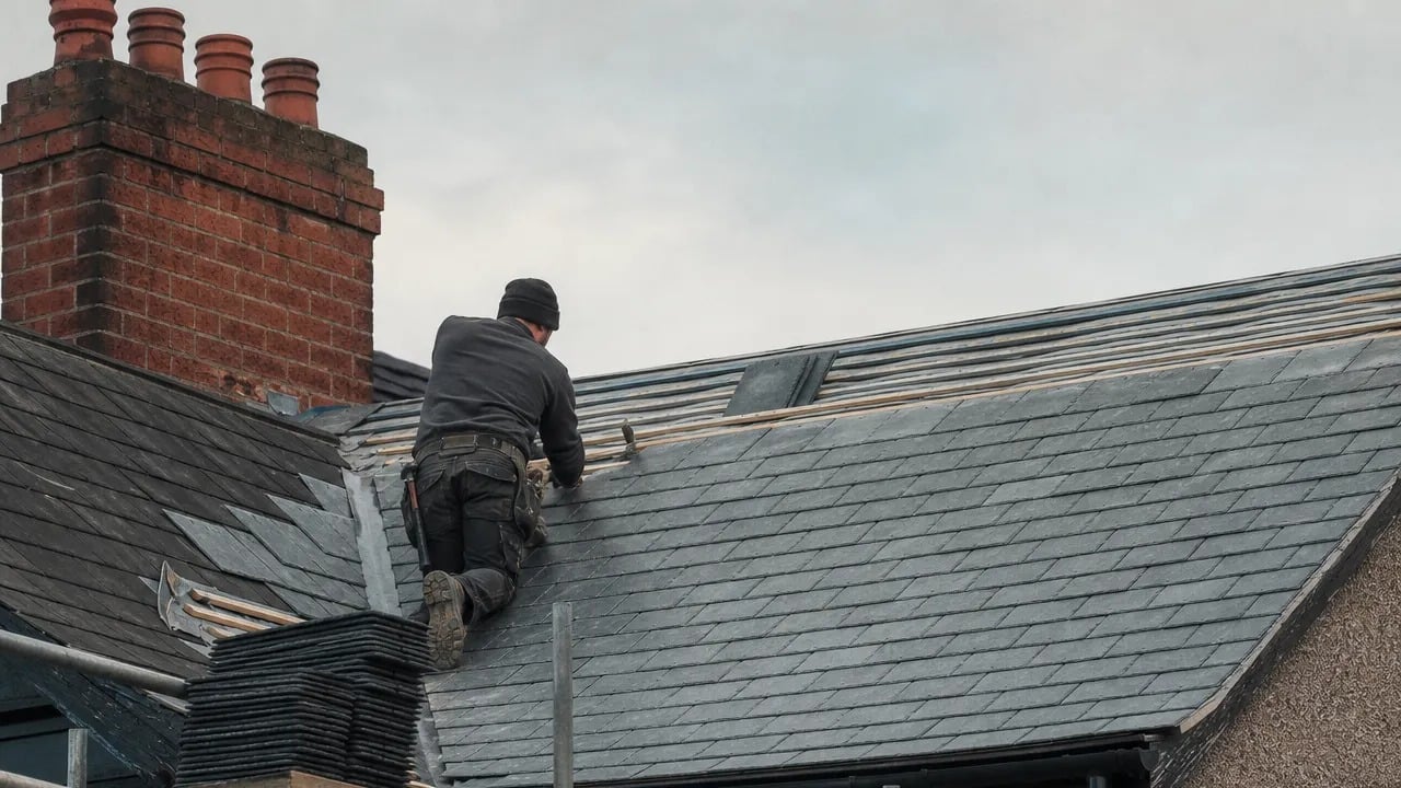 Roofer laying new slate tiles on a British house roof