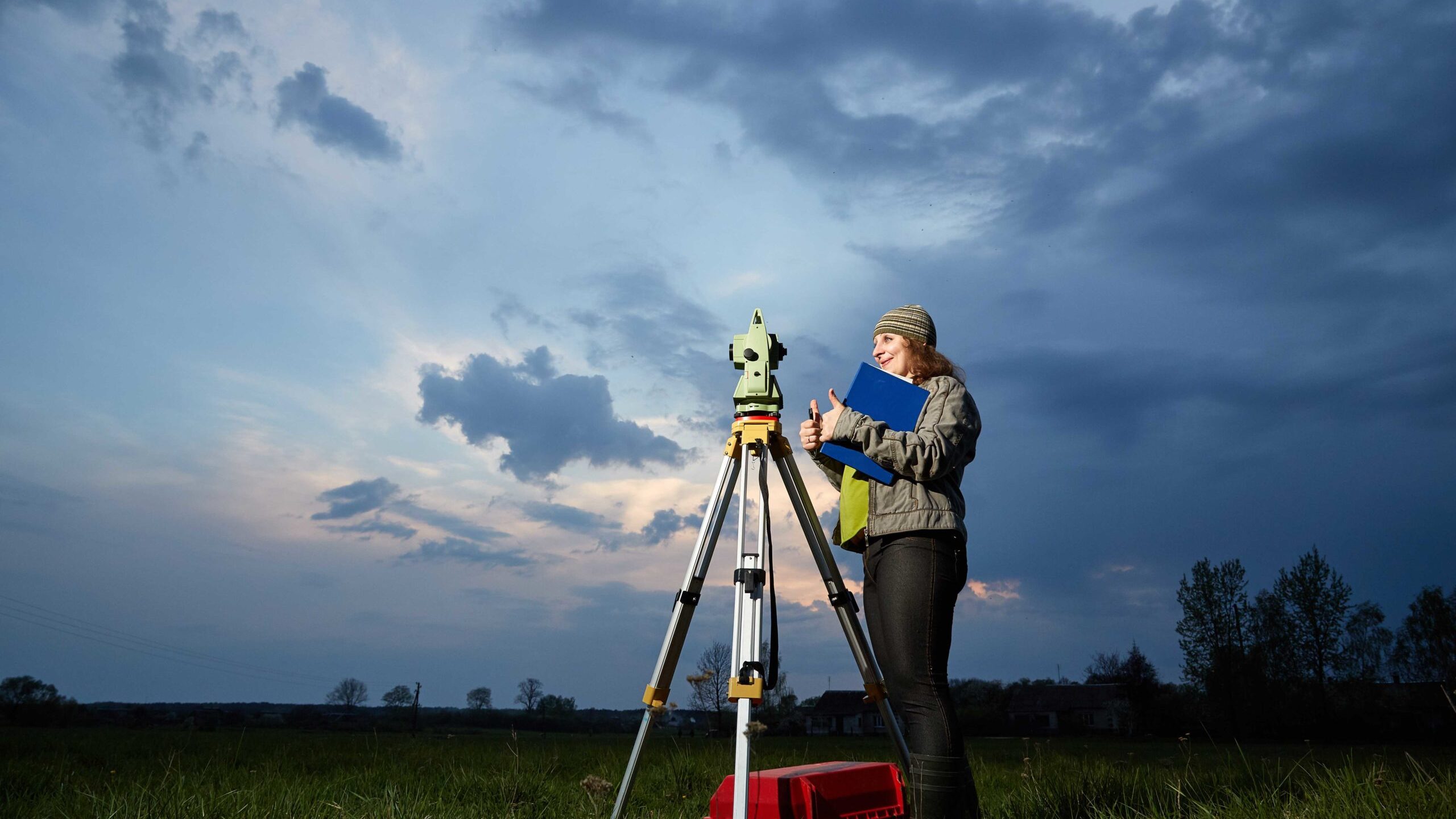 Surveyor using total station instrument on tripod for topographic measurements