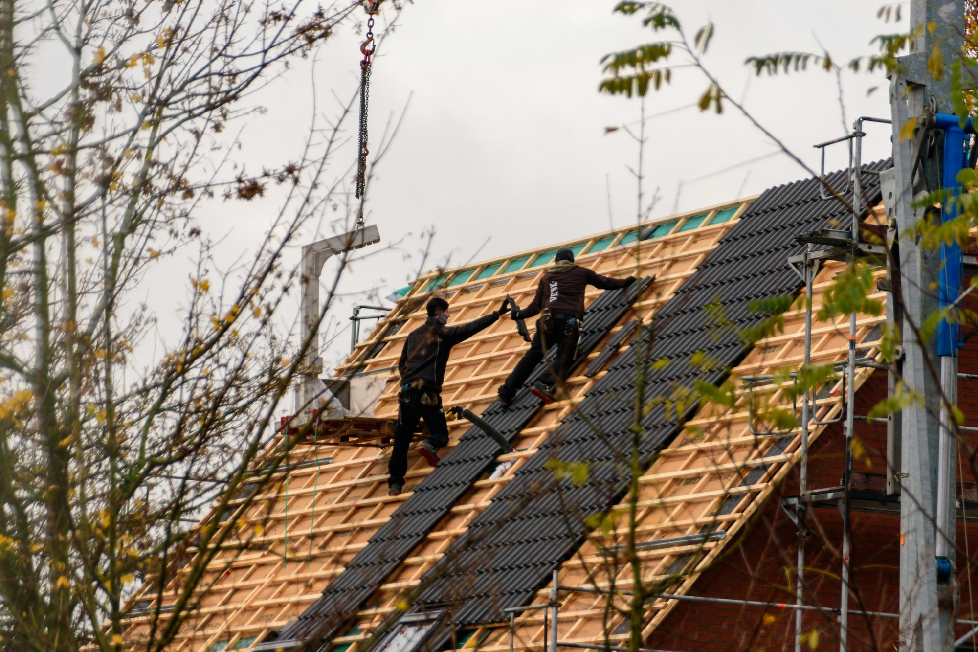 Roofers re-roofing a house with new battens and slates