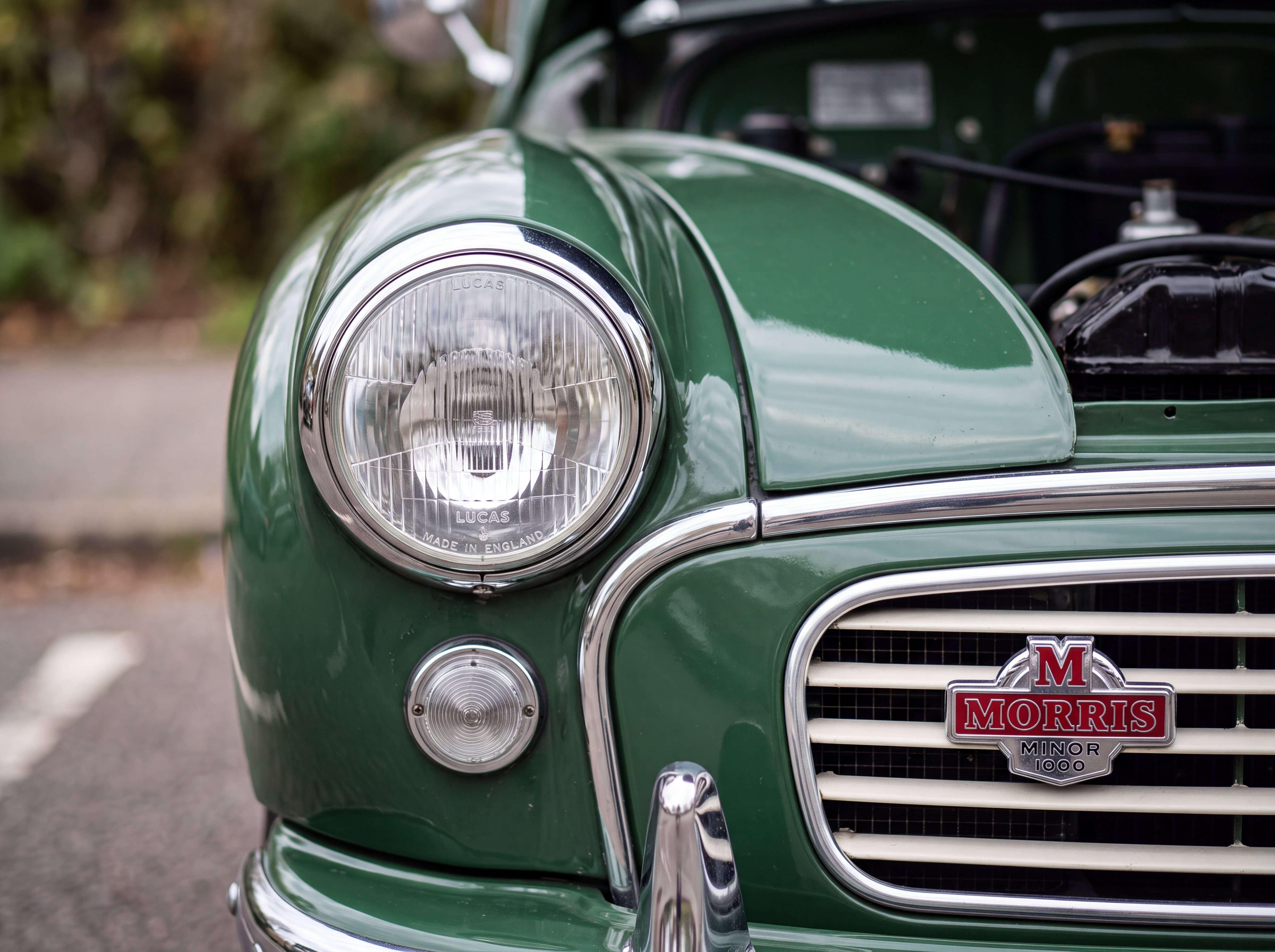 Close-up of the chrome headlight and green bodywork of a 1967 Morris Minor