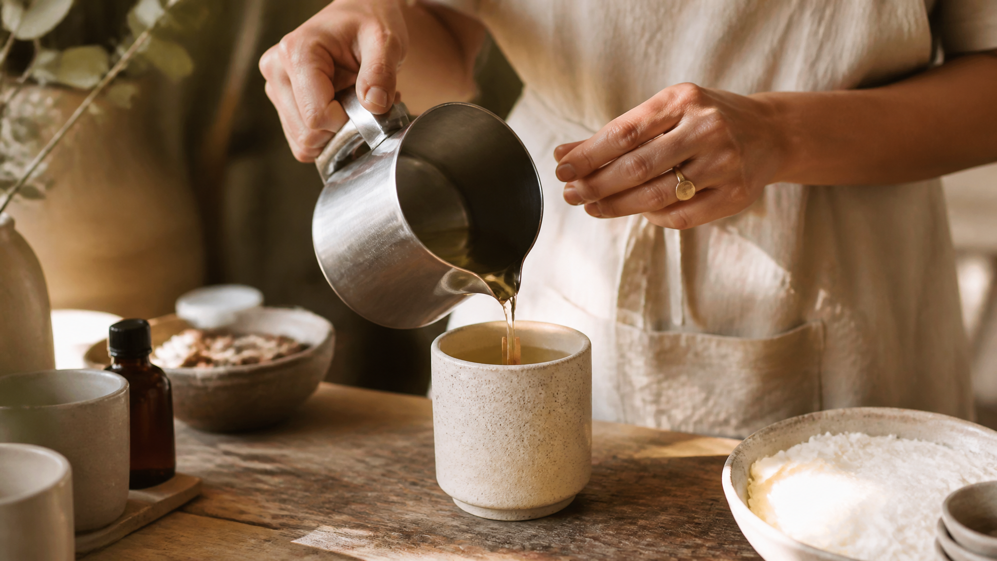 Artisan hands pouring soy wax into a ceramic candle vessel