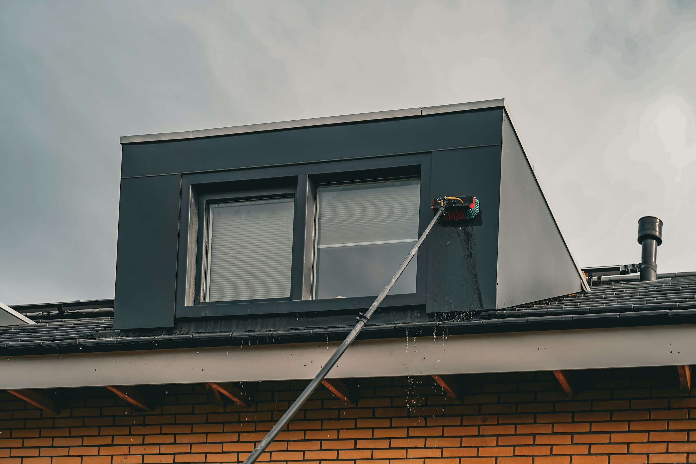 Gutter cleaning pole used on a dormer roof