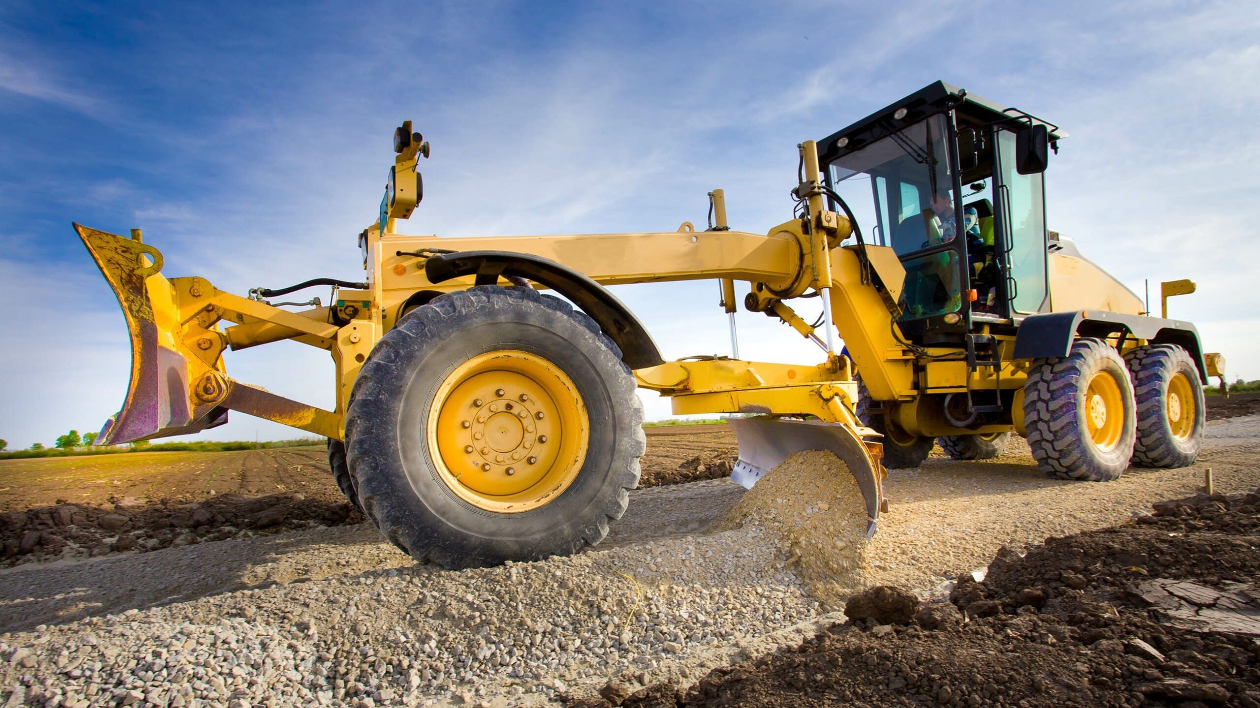 Motor grader performing precision road grading and finishing work