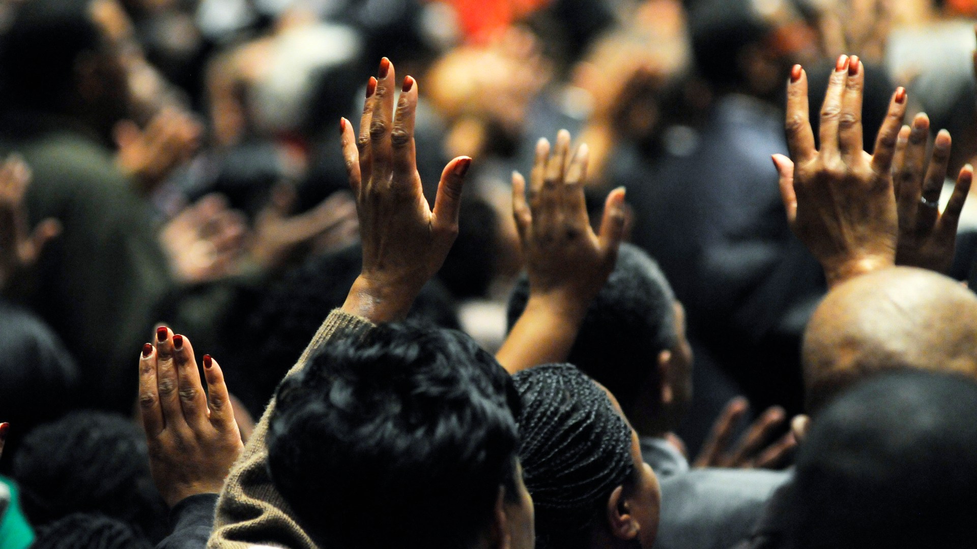 Church worship service with congregation raising hands in praise