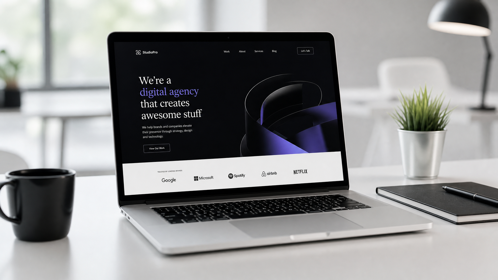 Professional laptop displaying creative agency website on a modern minimalist desk