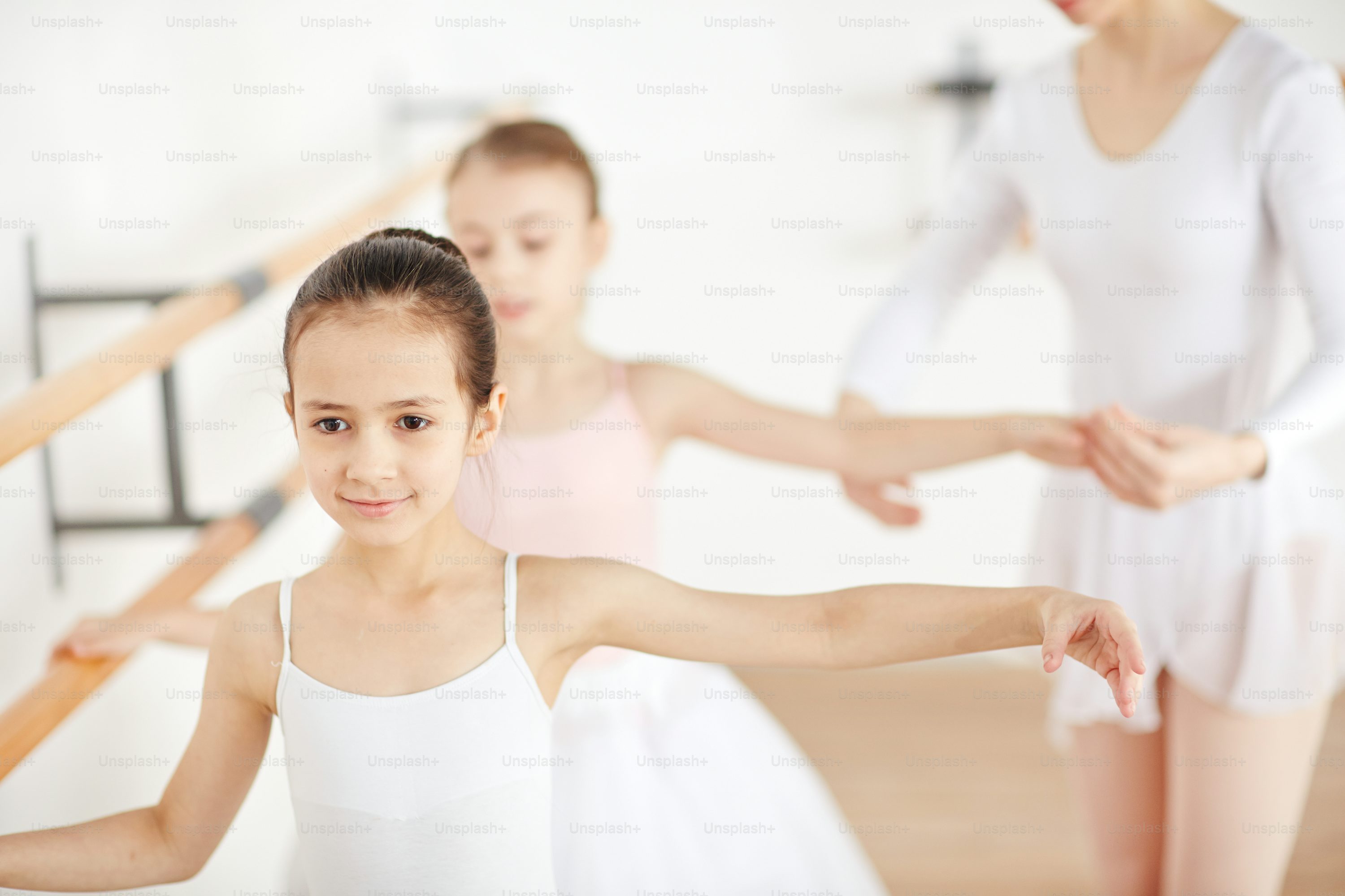 Dance teacher guiding young students in a warm studio setting