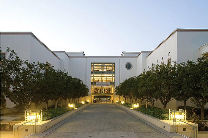 The Claremont Colleges campus building with tree-lined walkway at dusk