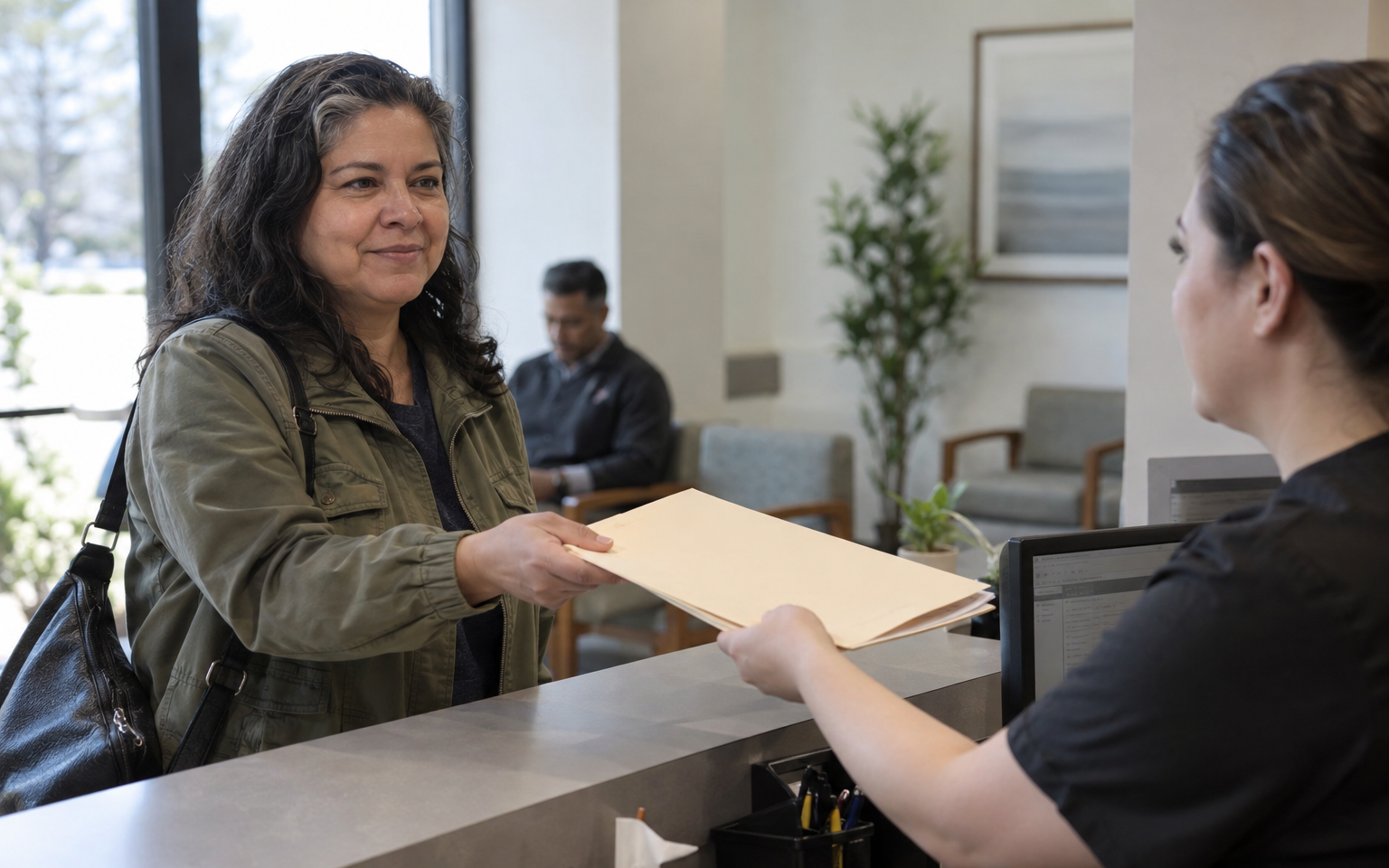 A woman veteran handing a folder of medical records to a receptionist