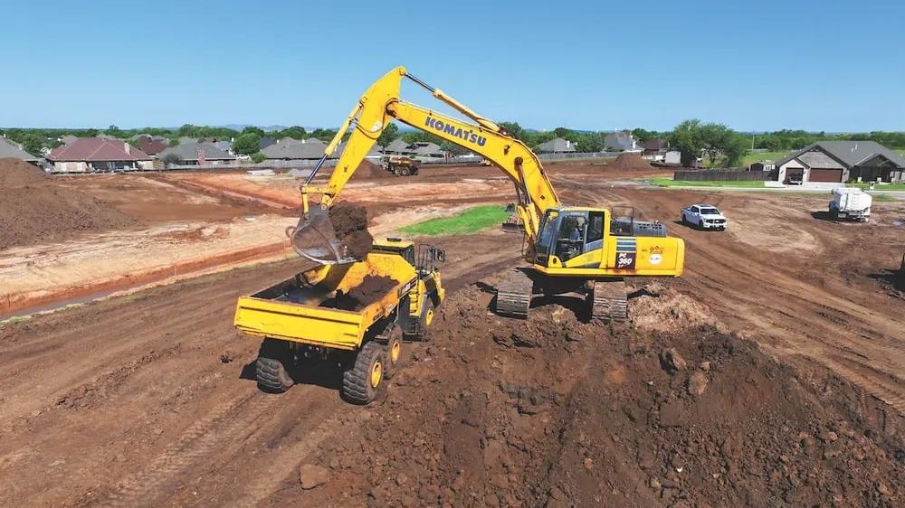 Excavator loading haul truck on large bulk earthworks site