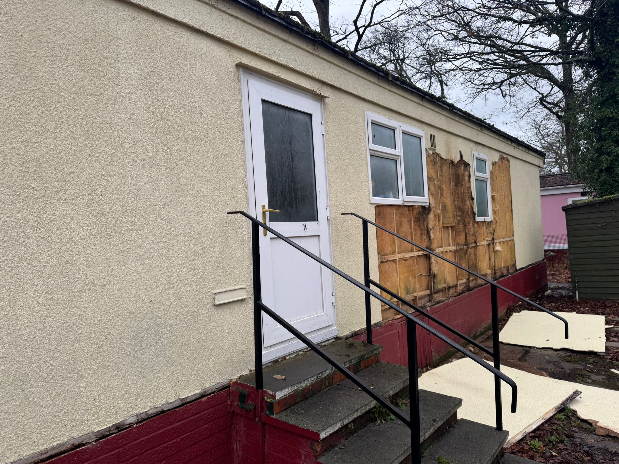 Park home exterior showing wall damage before repair work