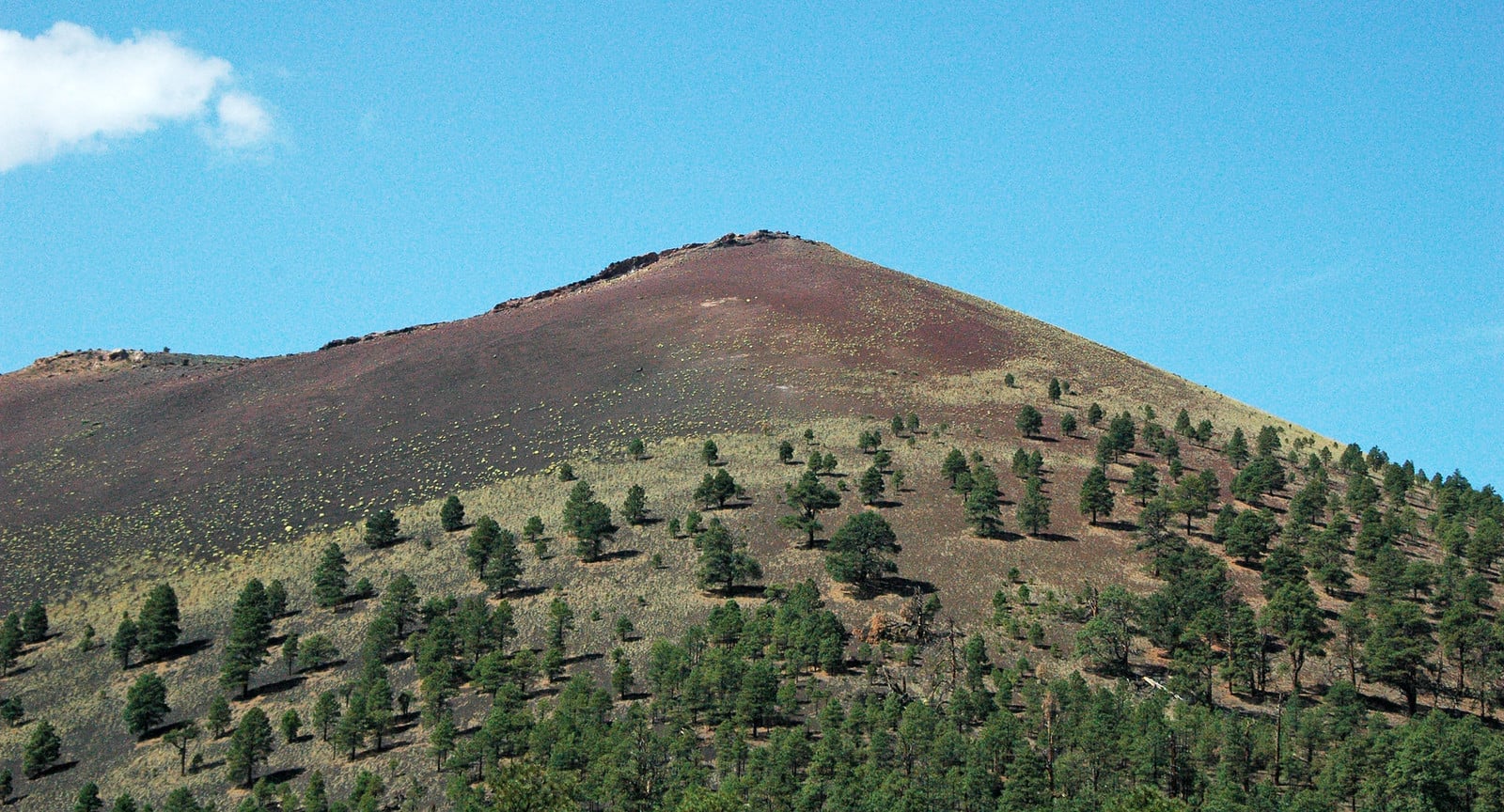A small steep-sided cinder cone volcano with a crater