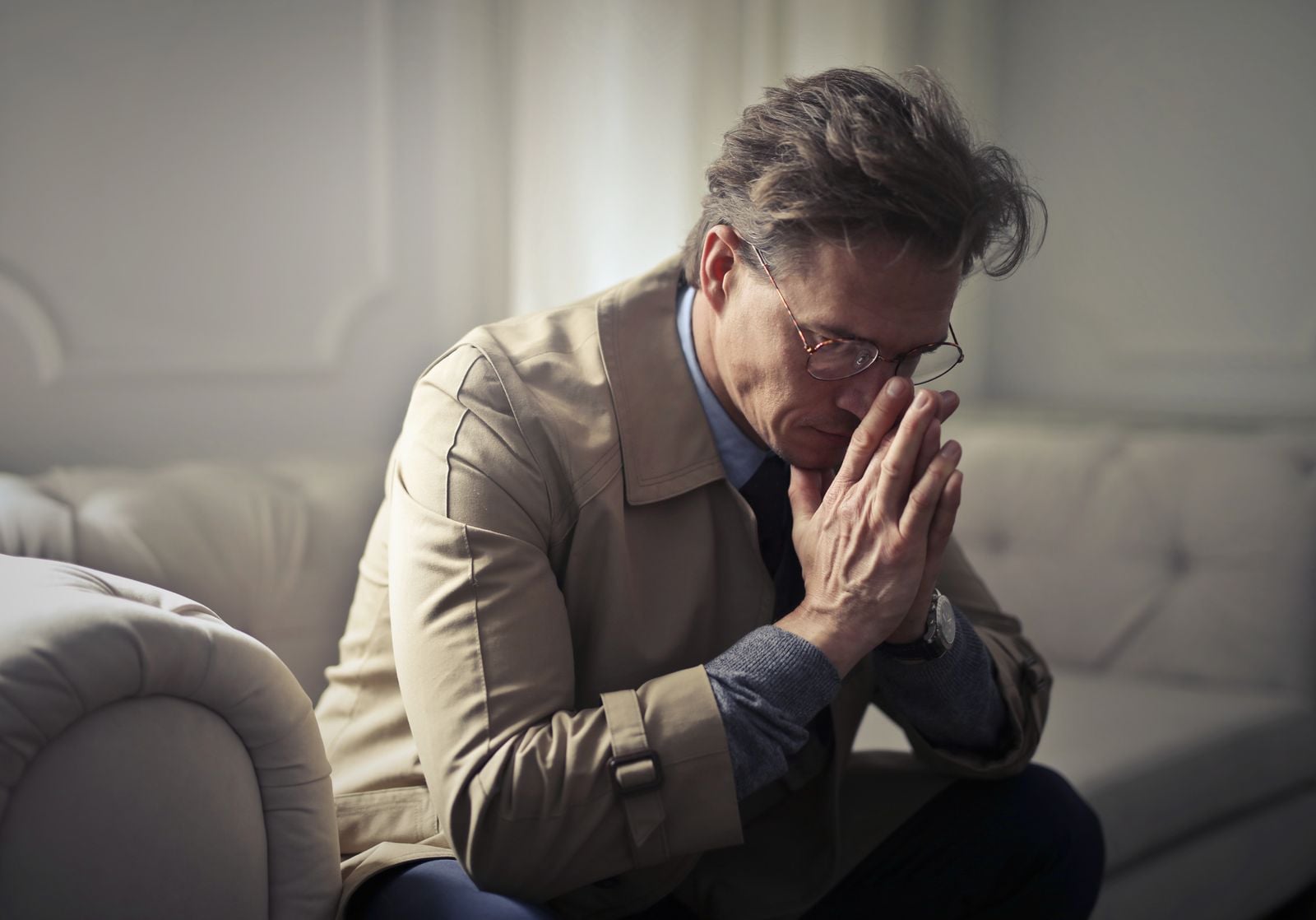An older man sitting at a desk with his hand to his head, appearing distracted and unable to concentrate