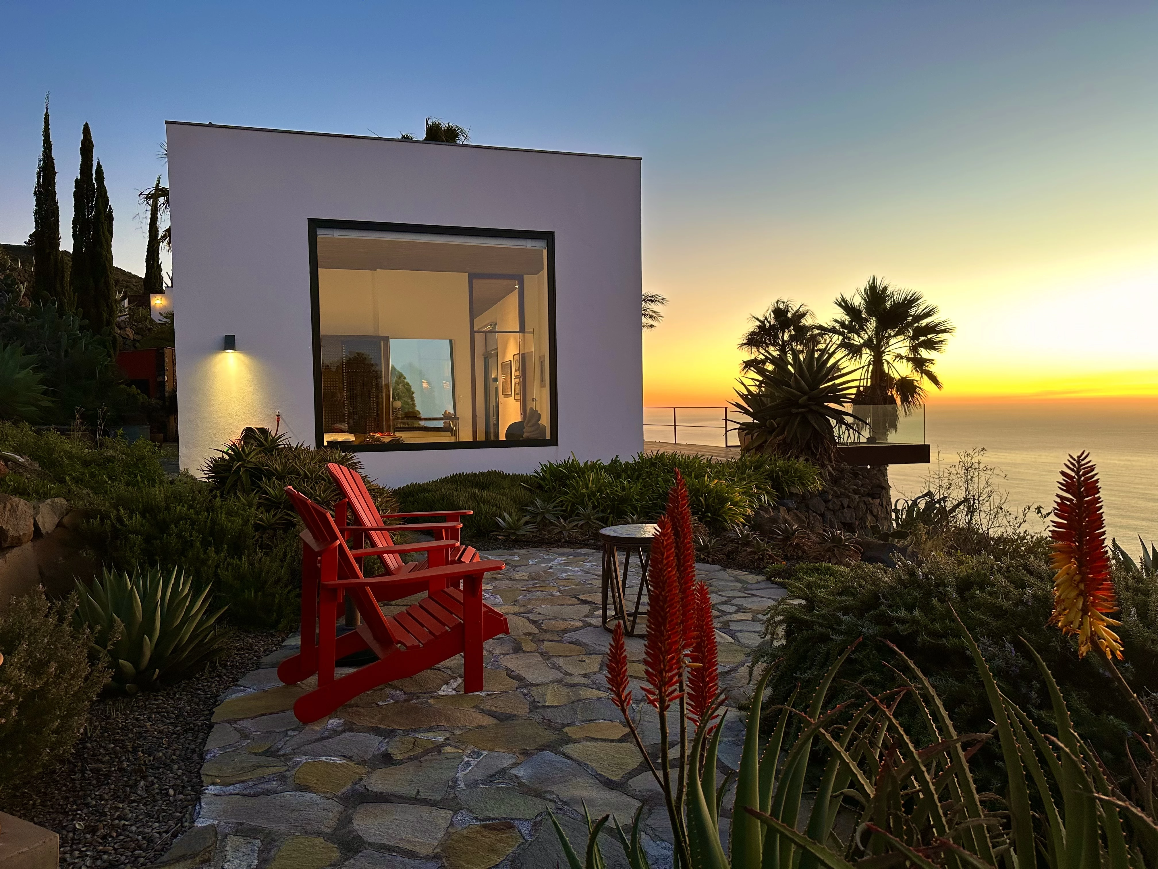 Villa entrance with pool, cacti garden and red chairs