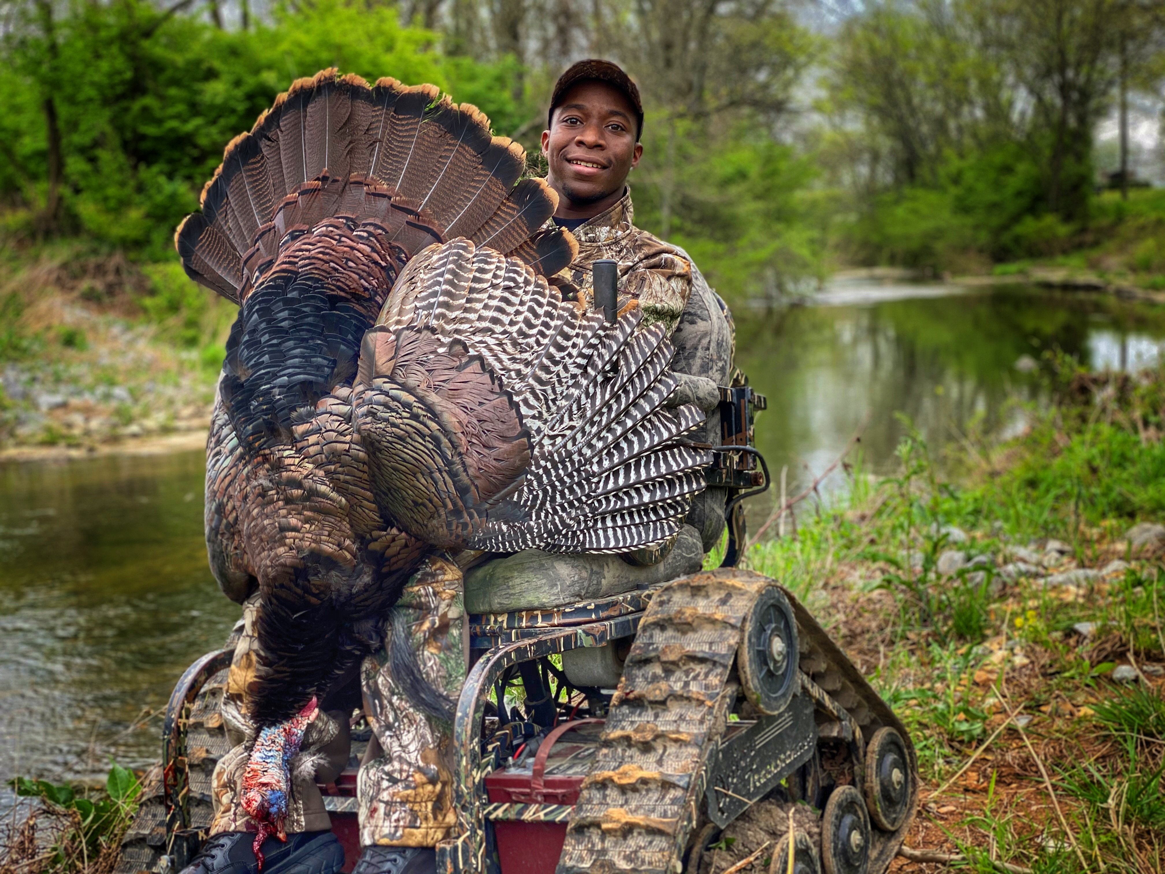 Joshua Carney with a trophy Eastern wild turkey by the river