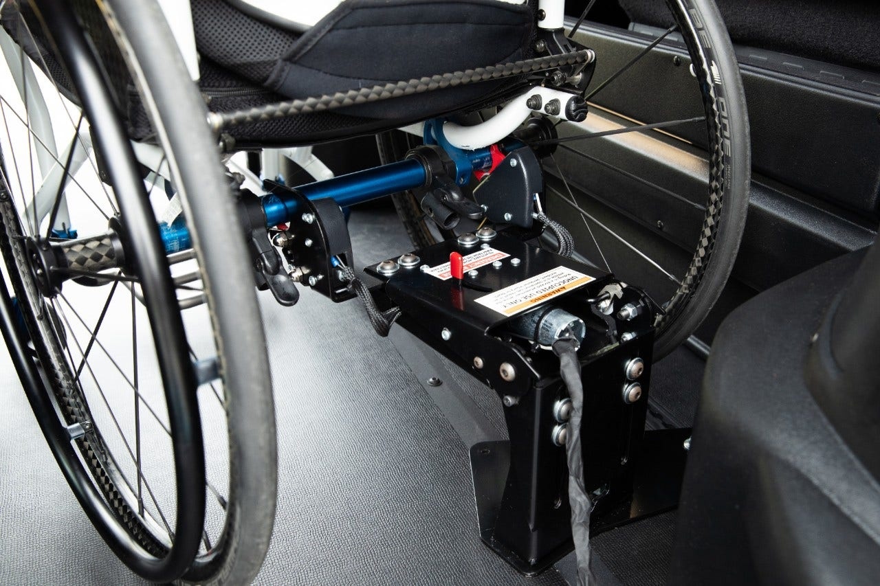 Driver securing wheelchair with tie-down straps for safe transport