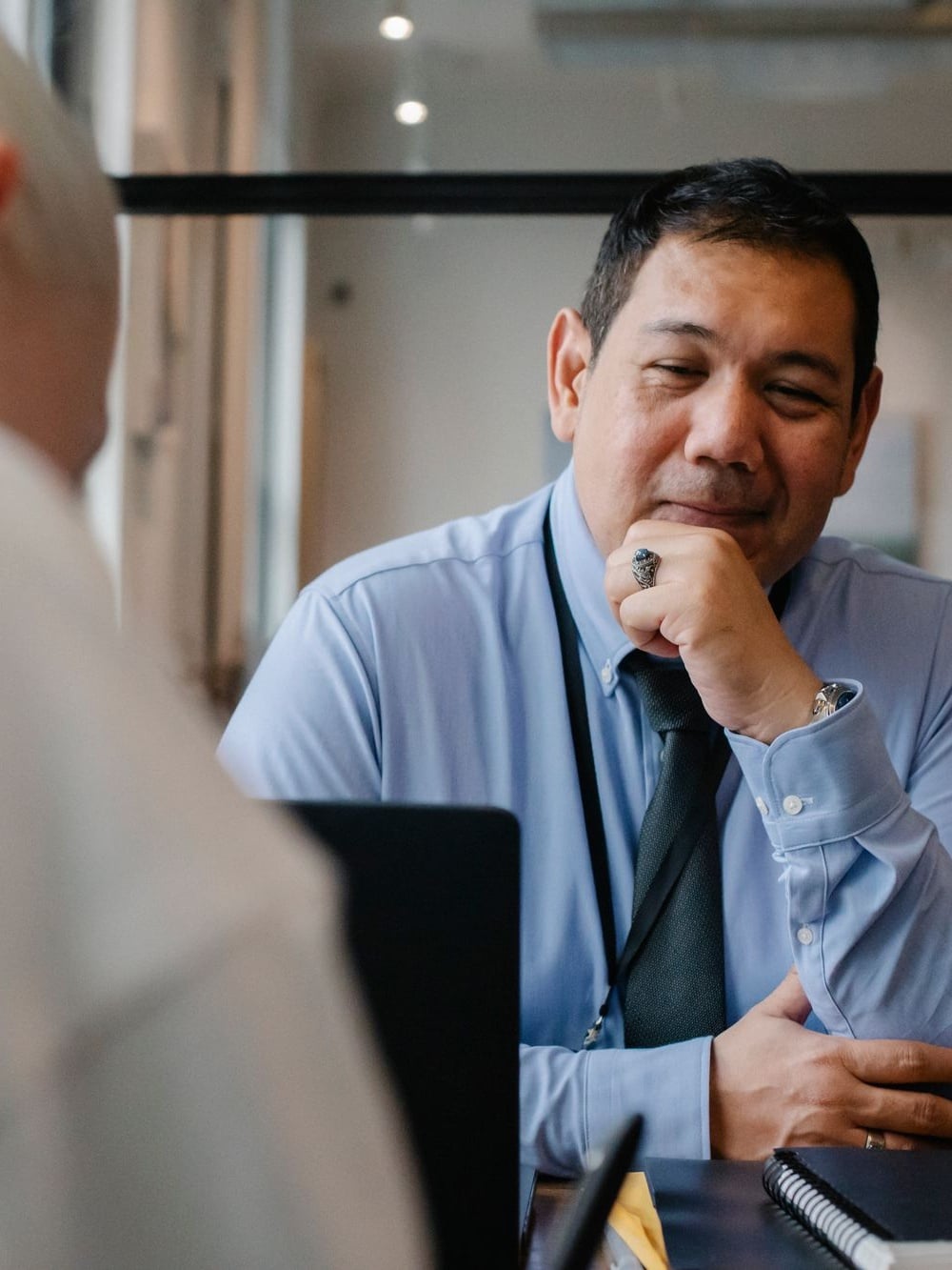 Professional portrait of a Filipino man in his 50s wearing a blue dress shirt and tie in a thoughtful pose serving as a veterans benefits advocate
