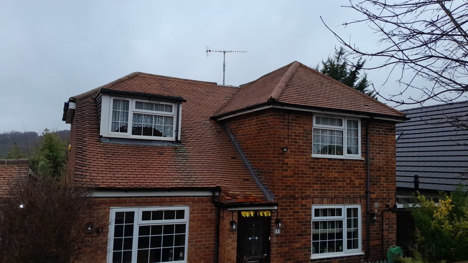 Clean red-brown tiled roof on a UK detached house