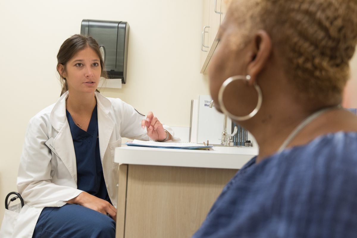 A female physician examining a senior patient in a clean medical exam room during a sleep medicine consultation