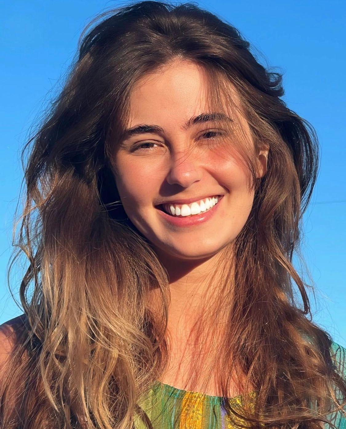 Ana smiling outdoors against a blue sky
