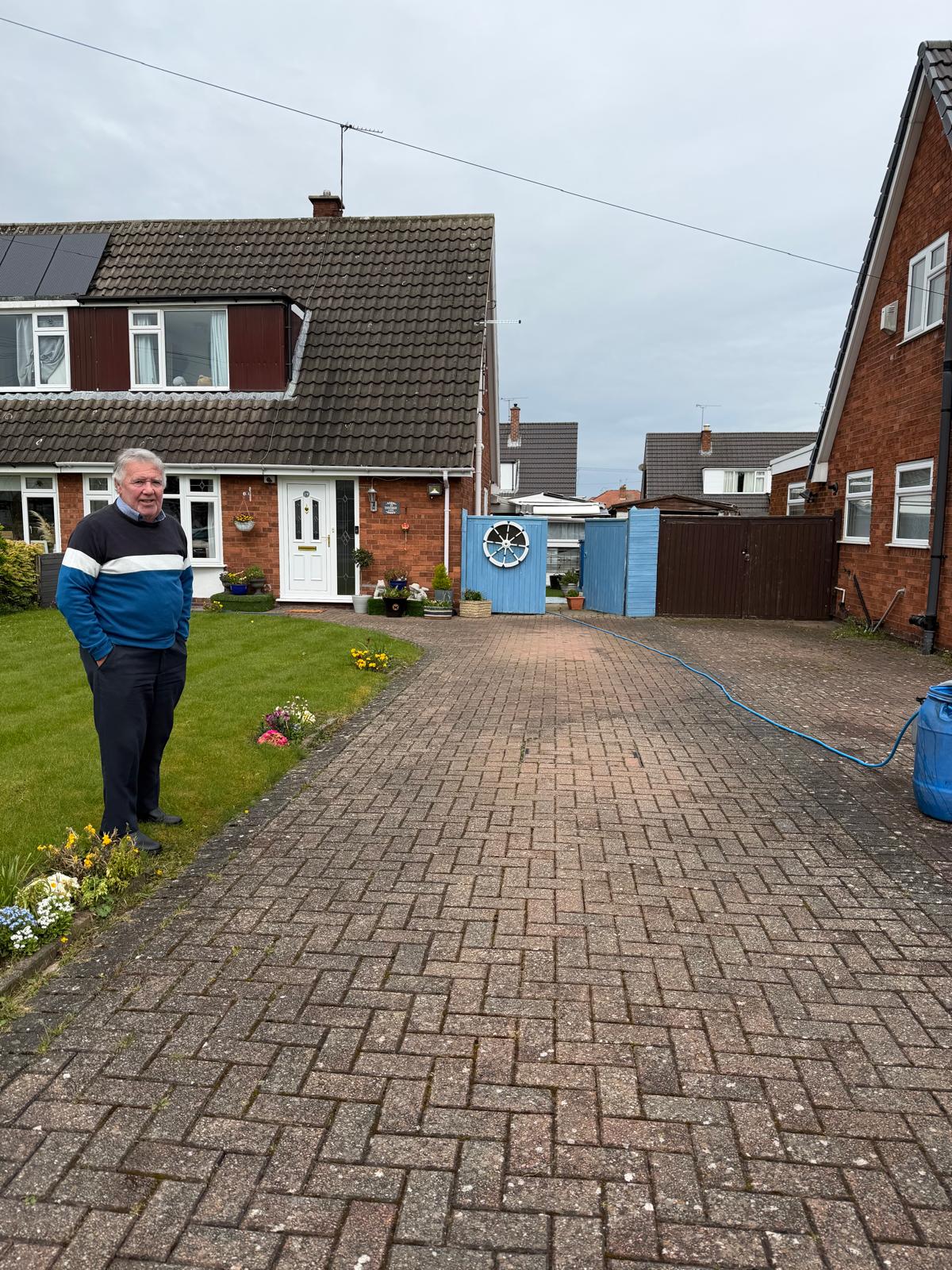 Smiling homeowner outside cleaned red-brick UK driveway