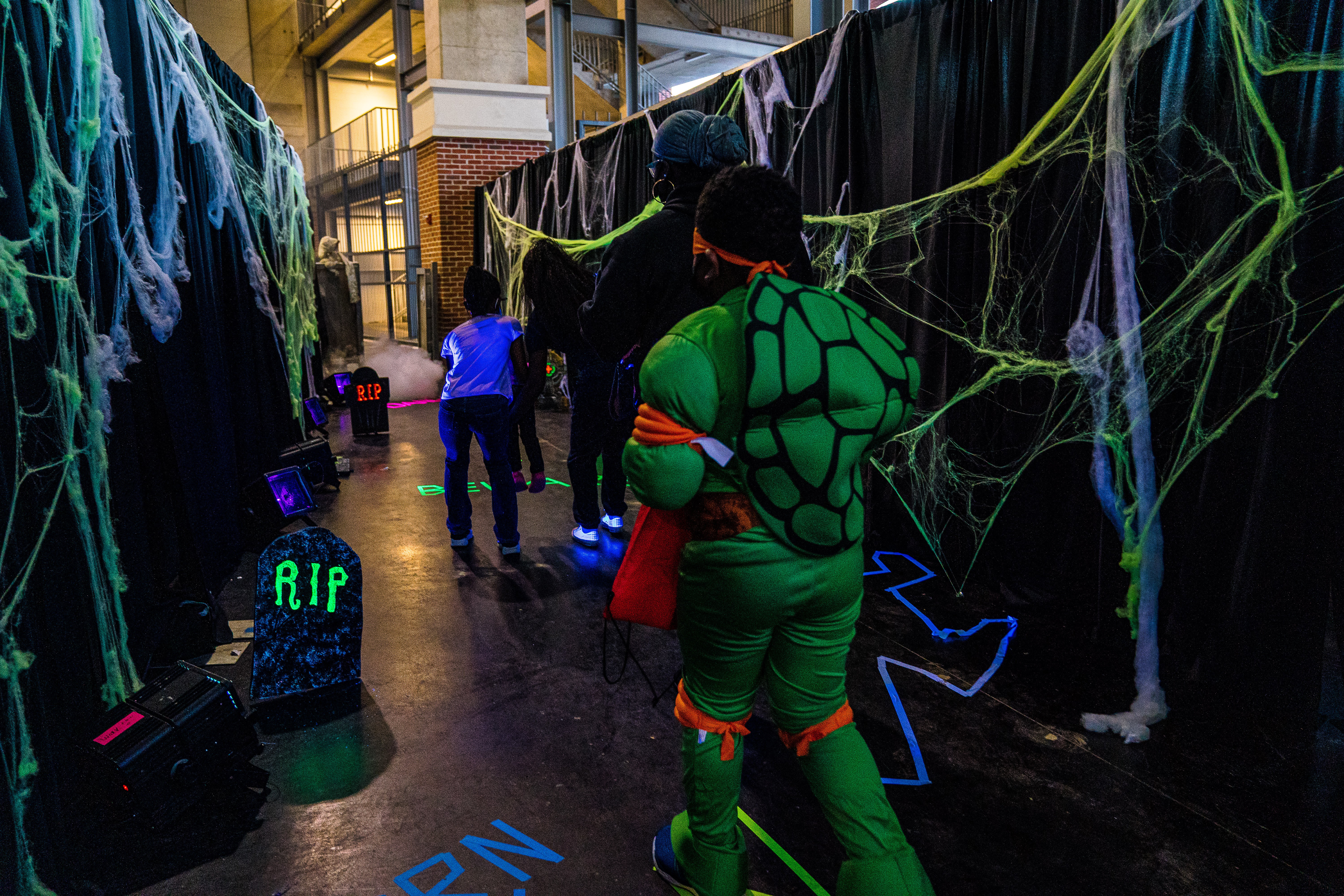 Kids walking through a spooky haunted maze with glowing spider webs and tombstones