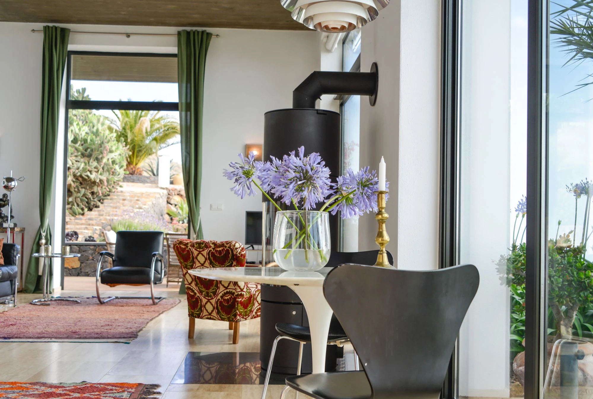 Living room with designer furniture, wood stove, and agapanthus flowers