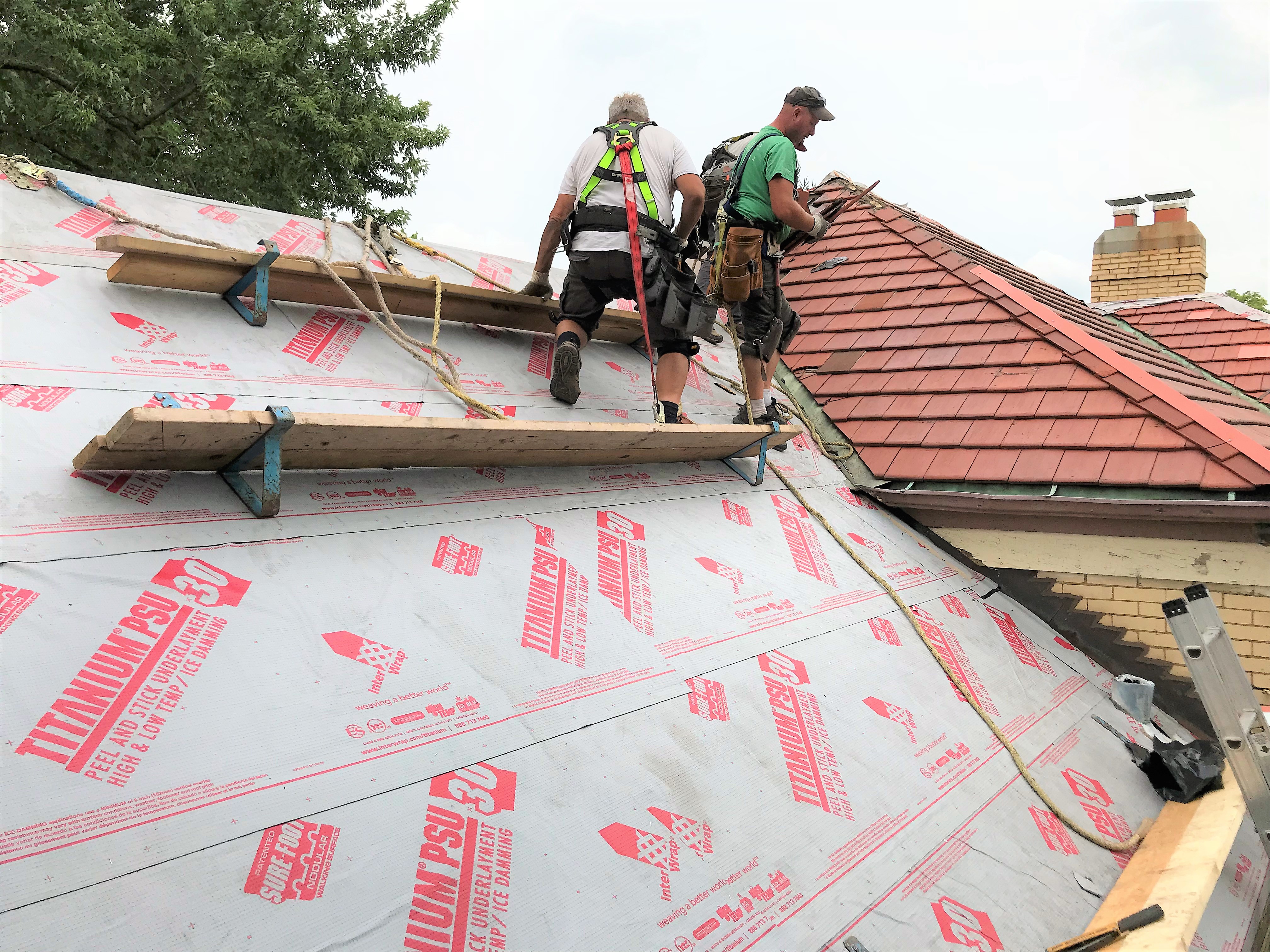 Roofers installing tiles on a pitched roof