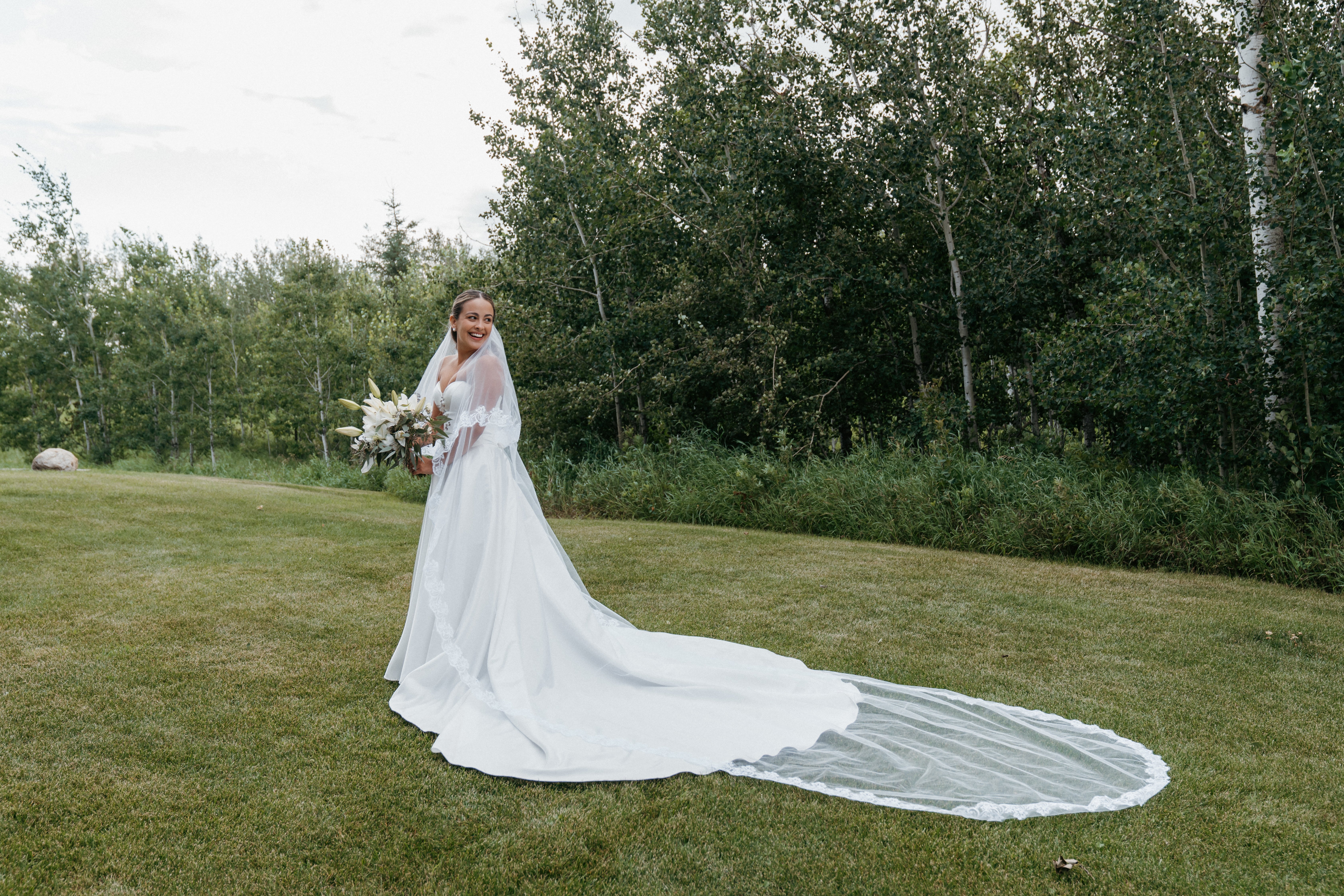 Bride with cathedral-length train and lily bouquet in a garden setting
