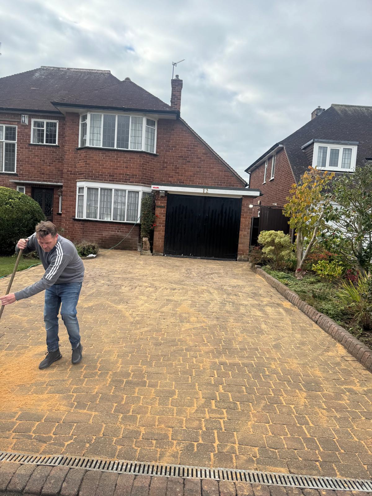 Large block paving driveway after - golden blocks with sand being swept in