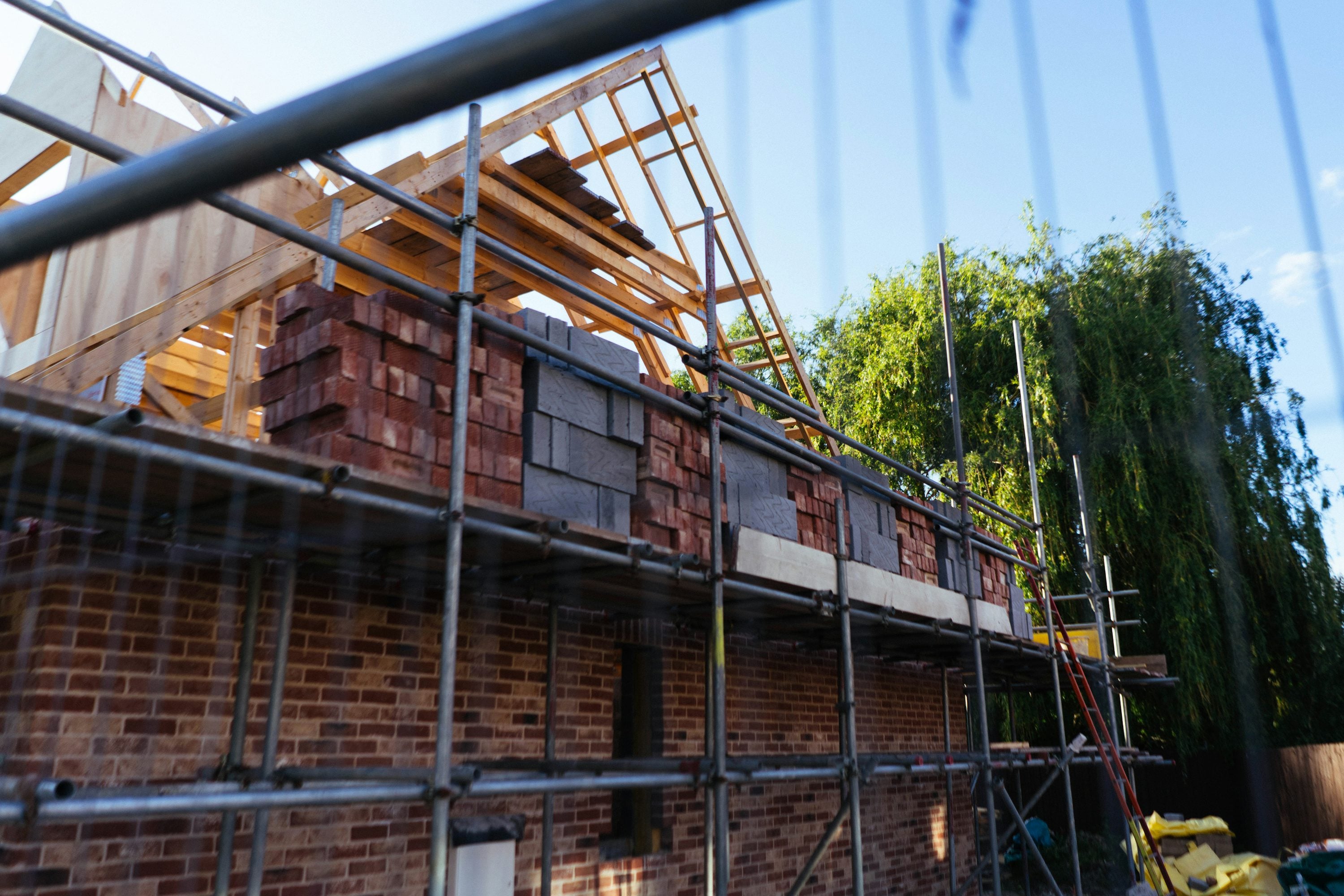 New roof structure with scaffolding on a brick house